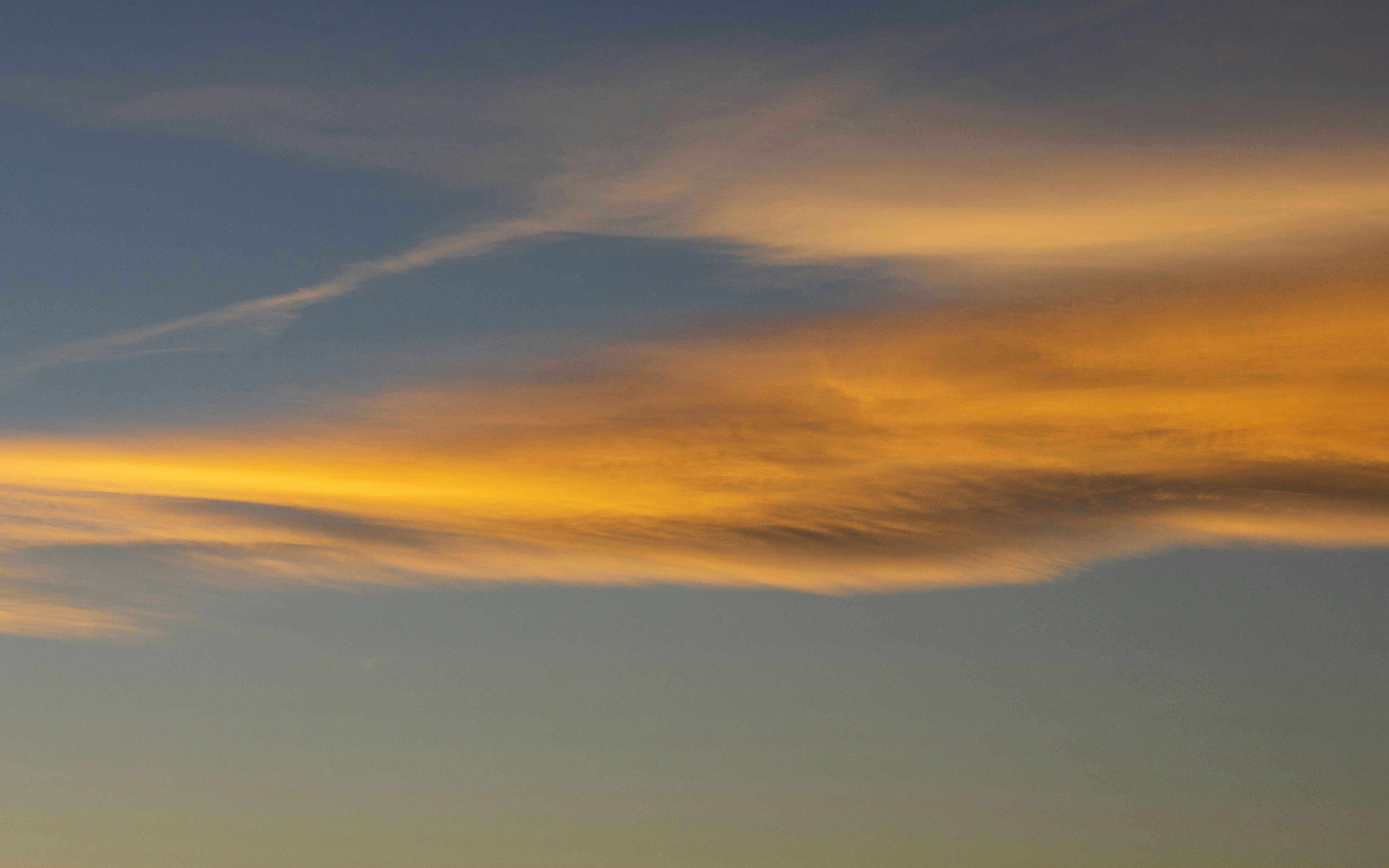 Goldene Wolken ziehen über einen blauen Himmel.