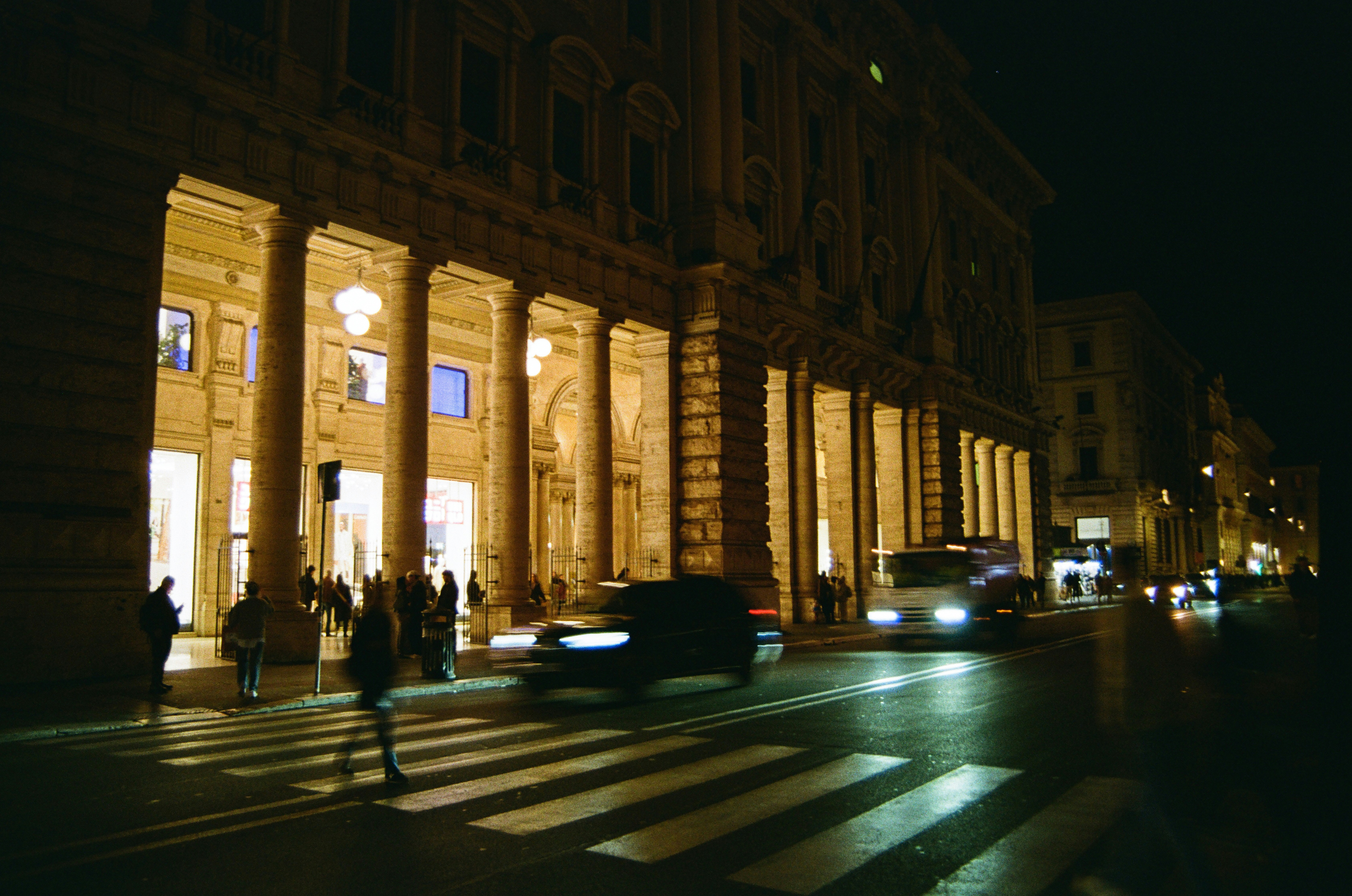 City street at night with illuminated buildings and traffic.