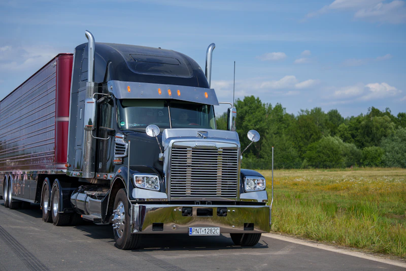 American Freightliner conventional tractor hauling a dry van on a North American highway