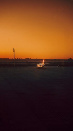 A private plane on an airport tarmac with luggage being loaded at sunset