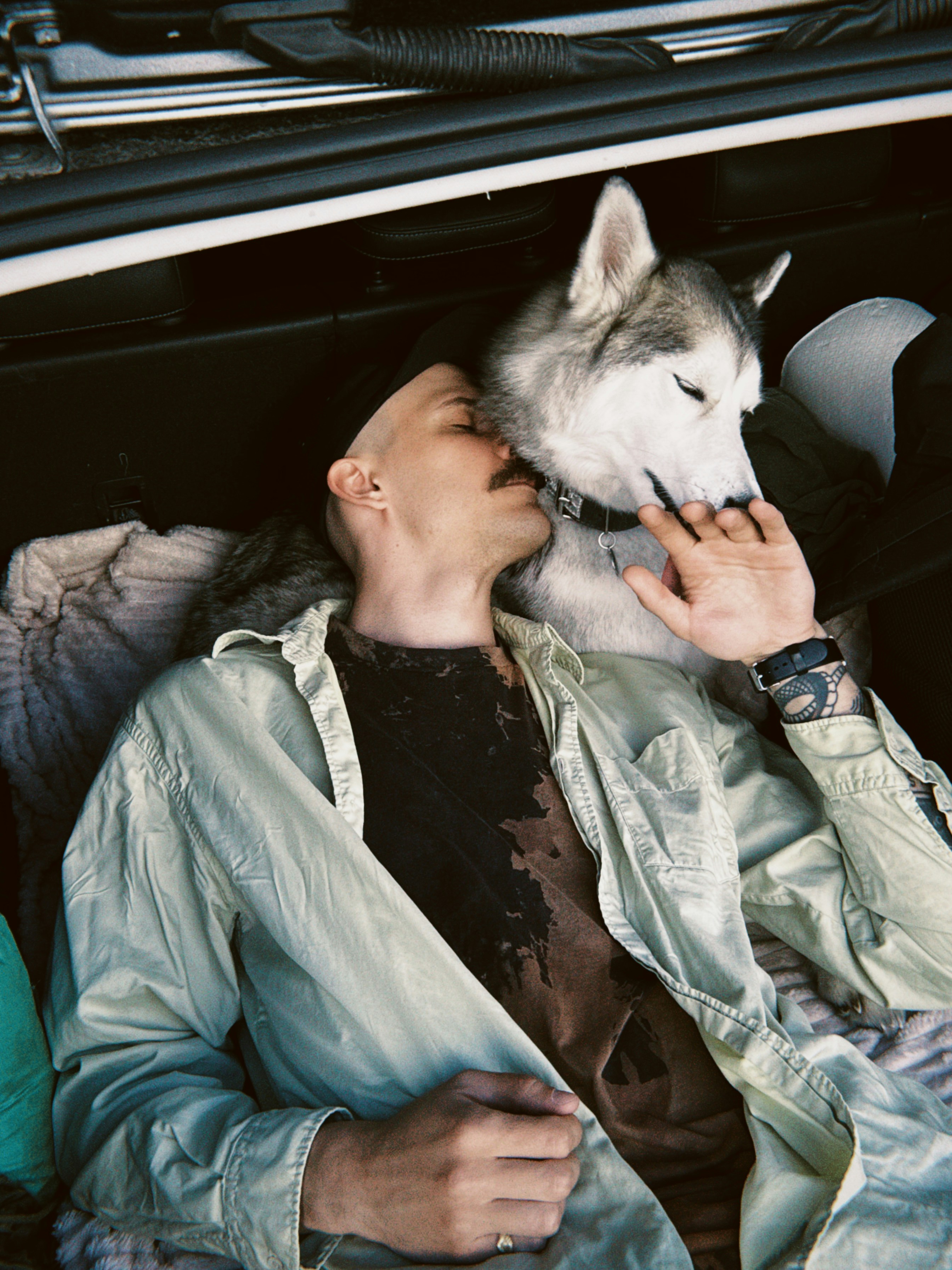 Uomo e cane husky che riposano insieme in macchina