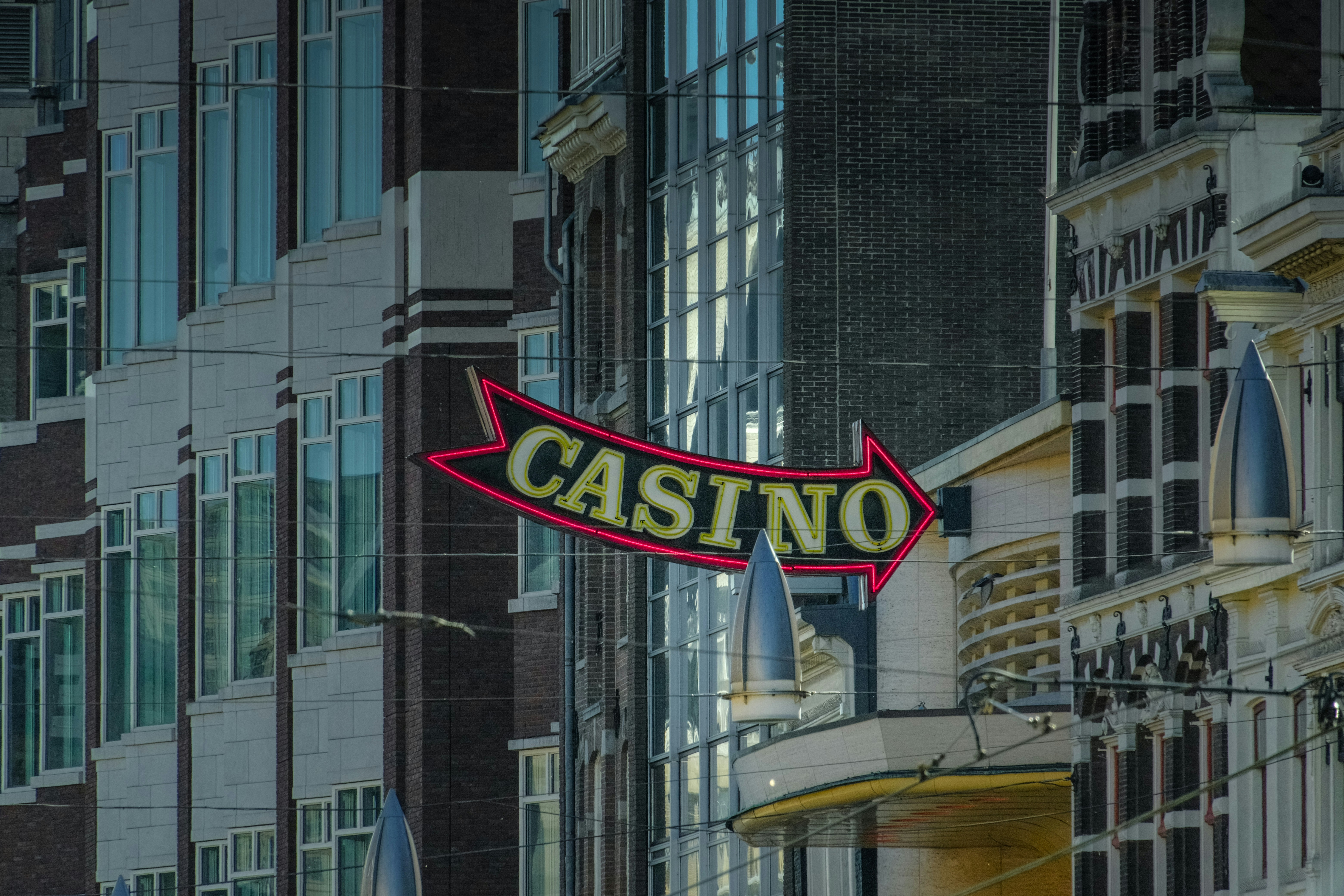Neon casino sign points right against buildings