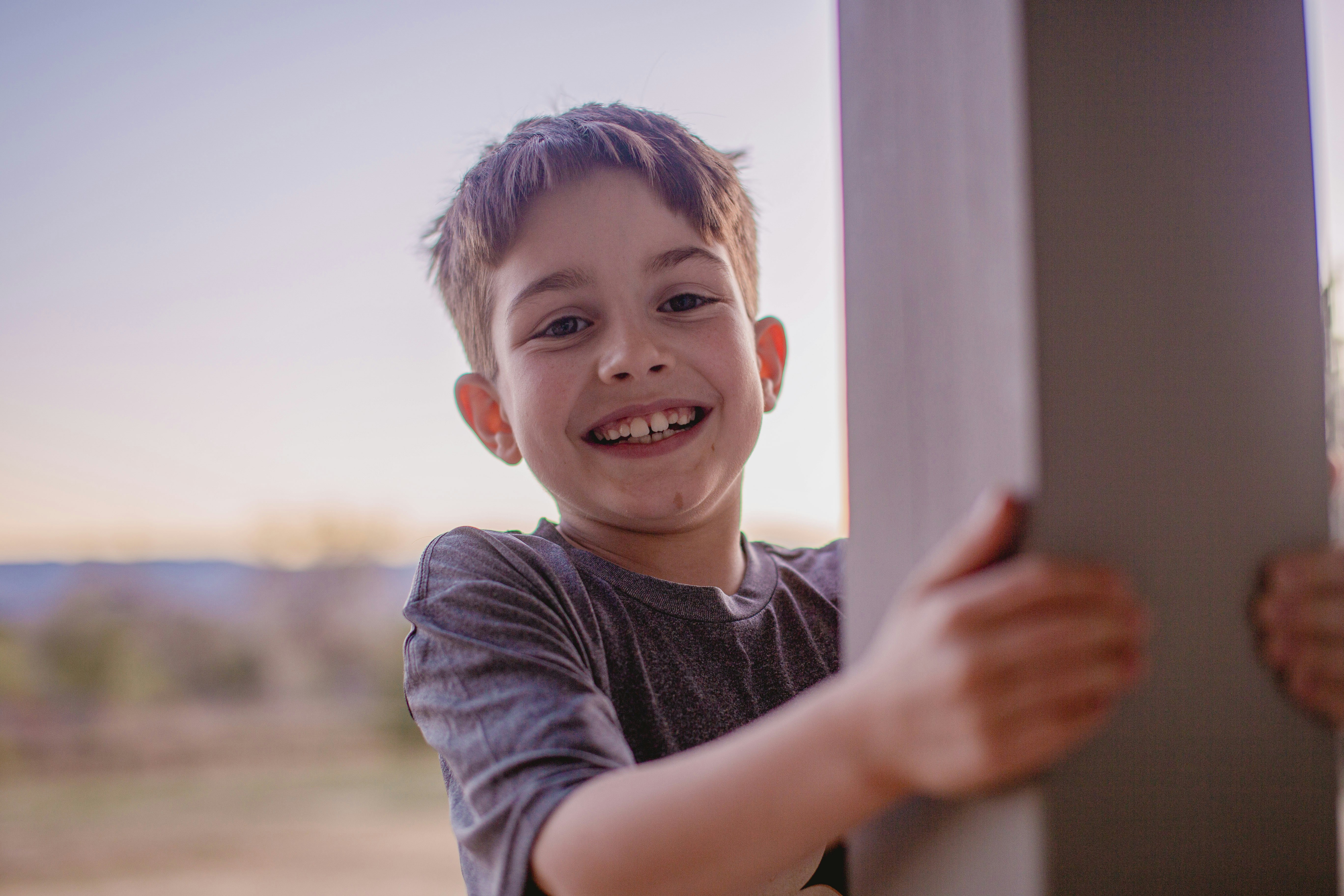 A smiling young boy peeking around a pillar