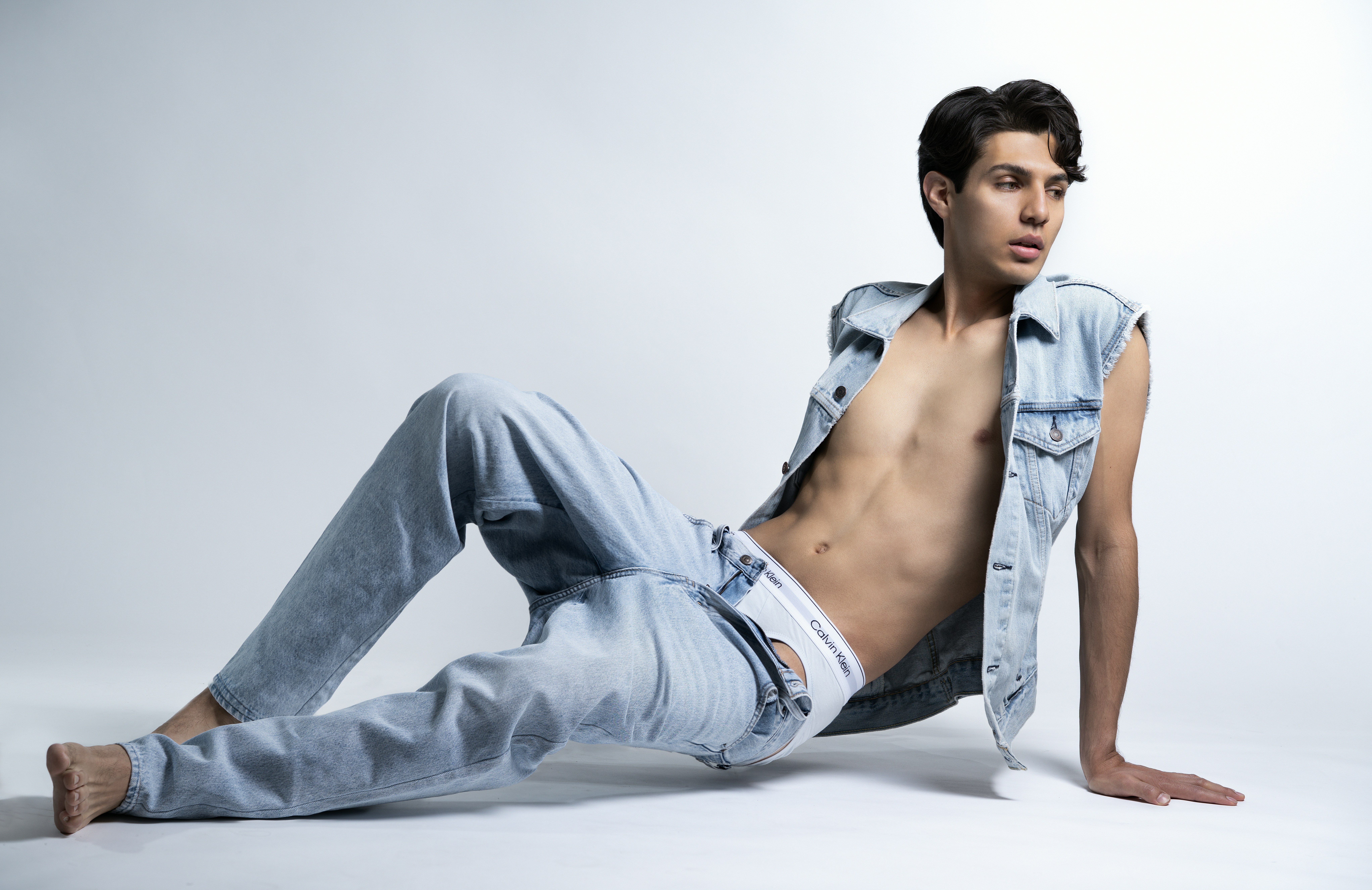Young man in denim vest and jeans posing