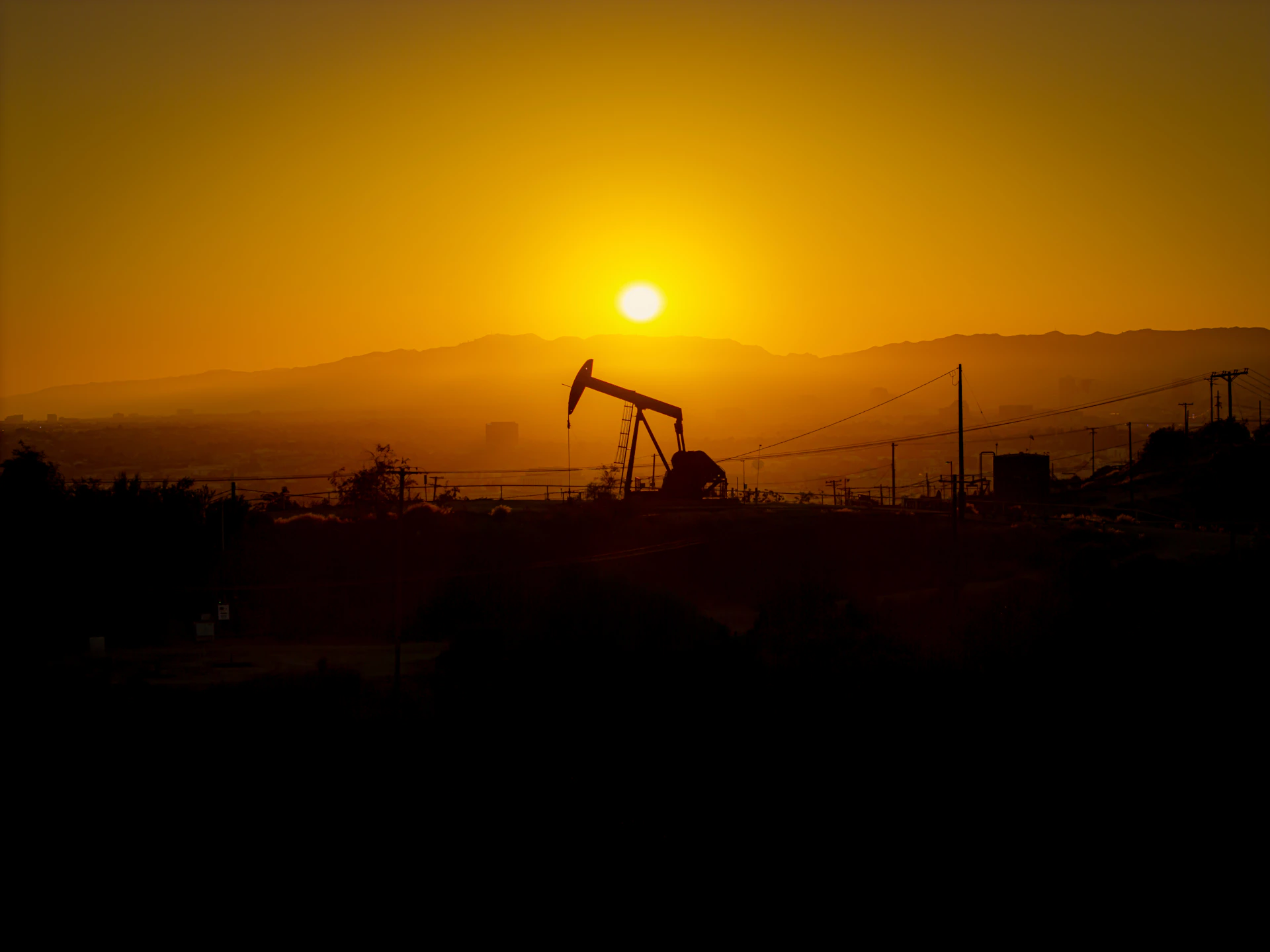 Oil pump jack silhouetted against a hazy sunset