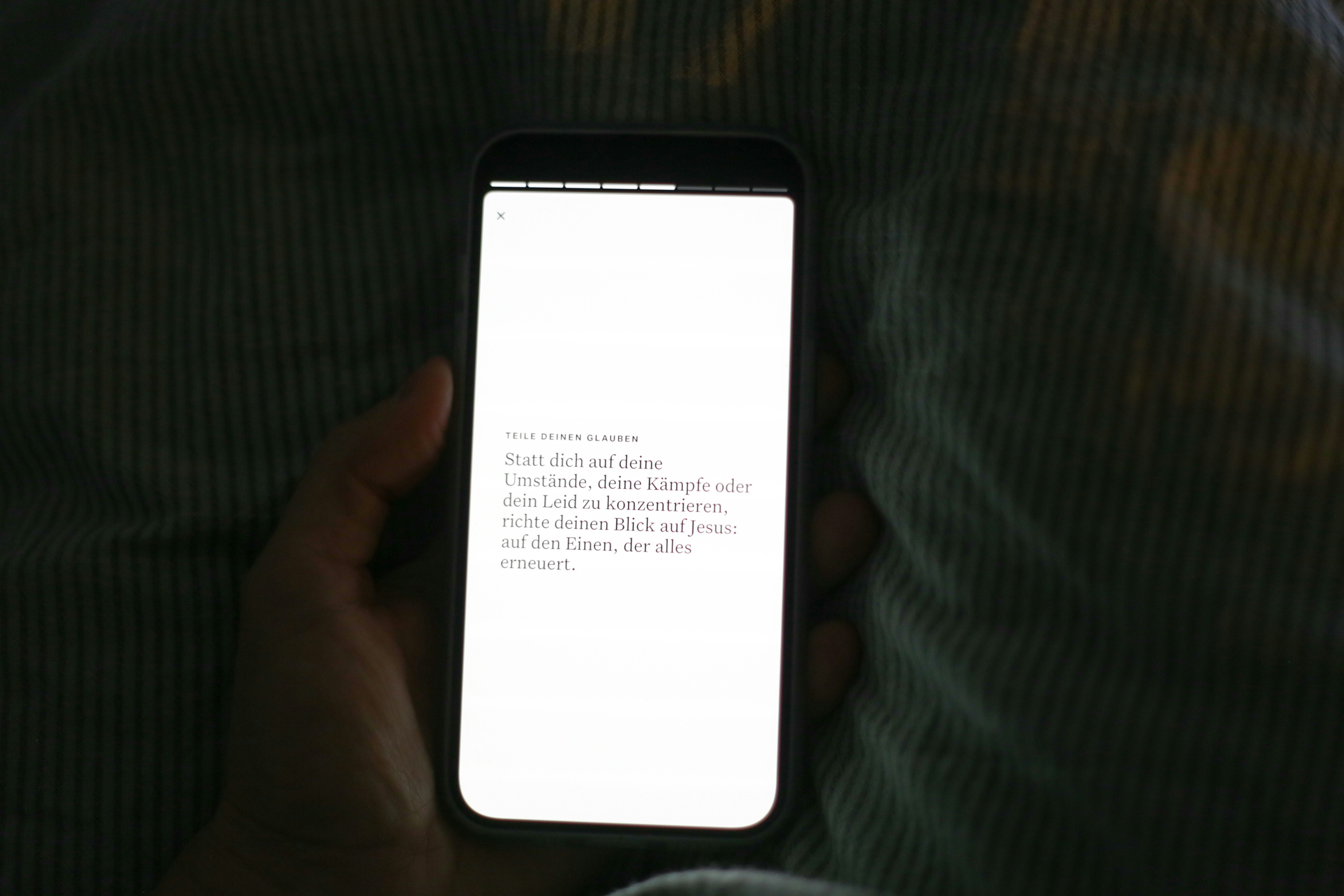 明るい白い画面のスマートフォンを手持ちで操作しています。