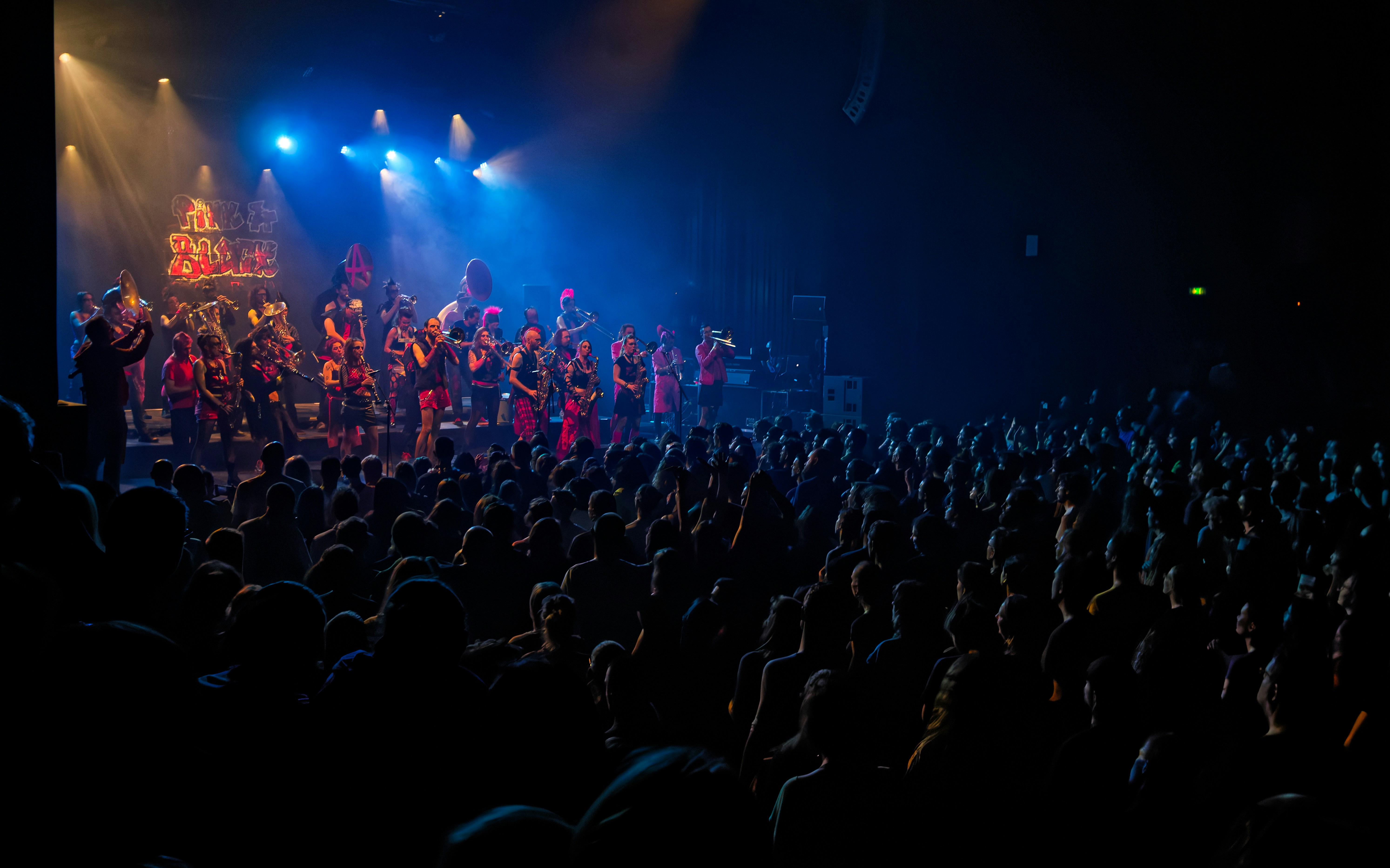 A large choir performs on a stage with blue lights.
