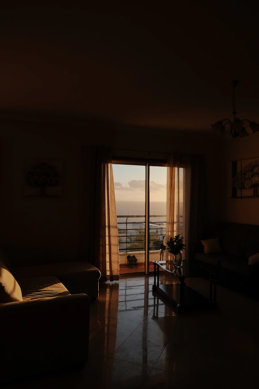 Spacious lounge with sofas opening onto a sea-view terrace at golden hour