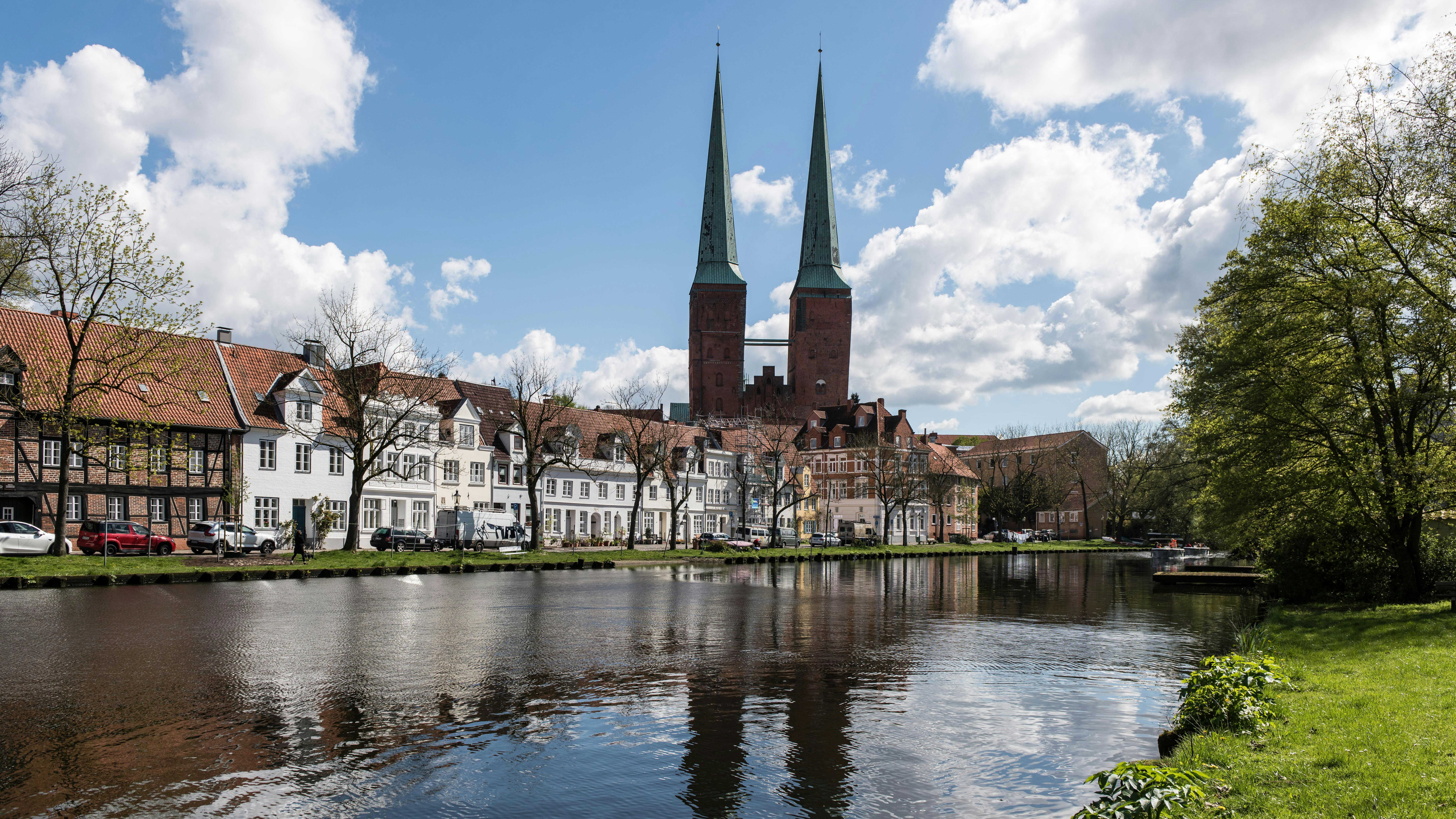 Edificios históricos bordean un canal con una catedral de dos agujas.