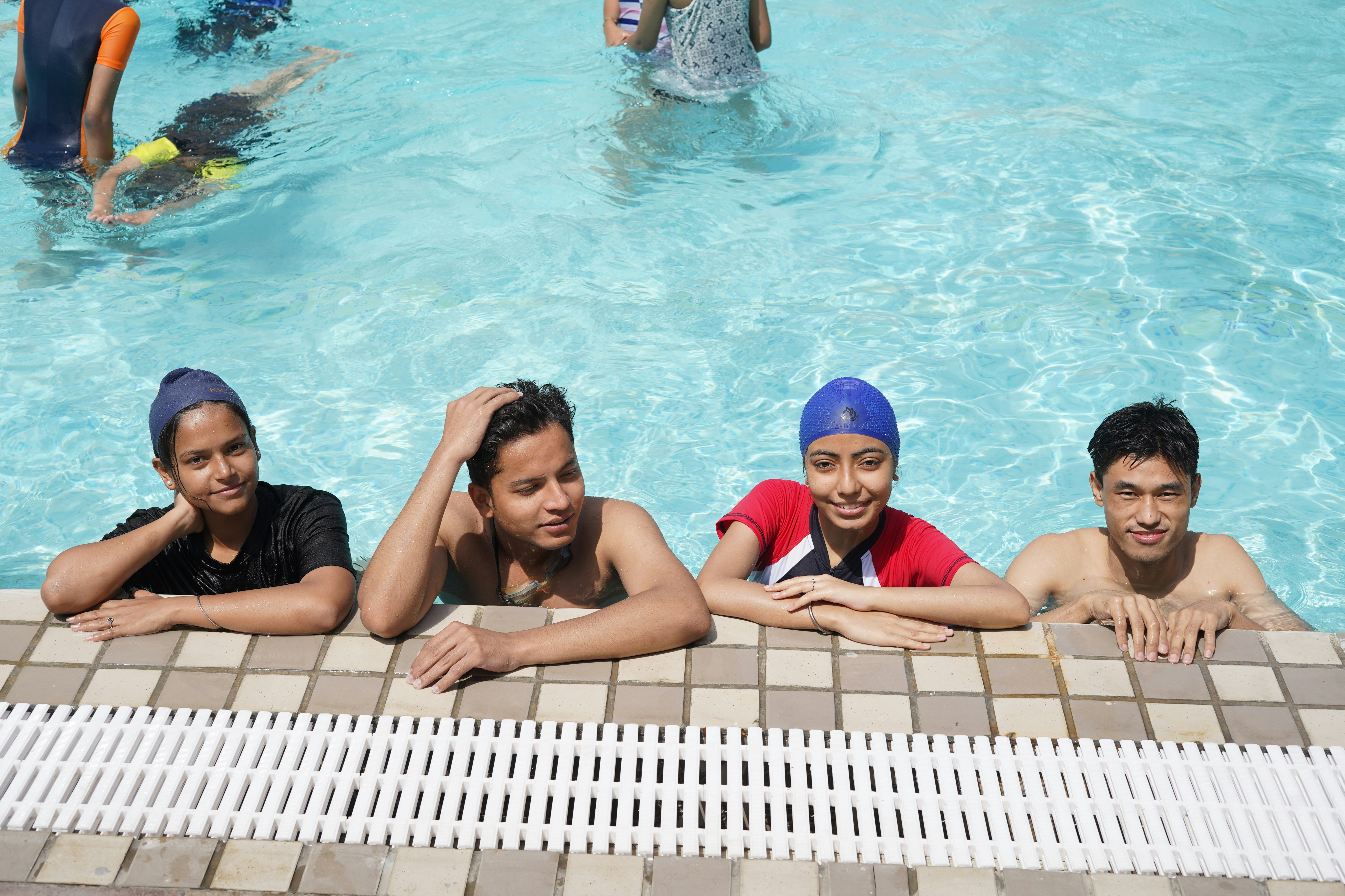 Quatre adolescents se reposant au bord d’une piscine