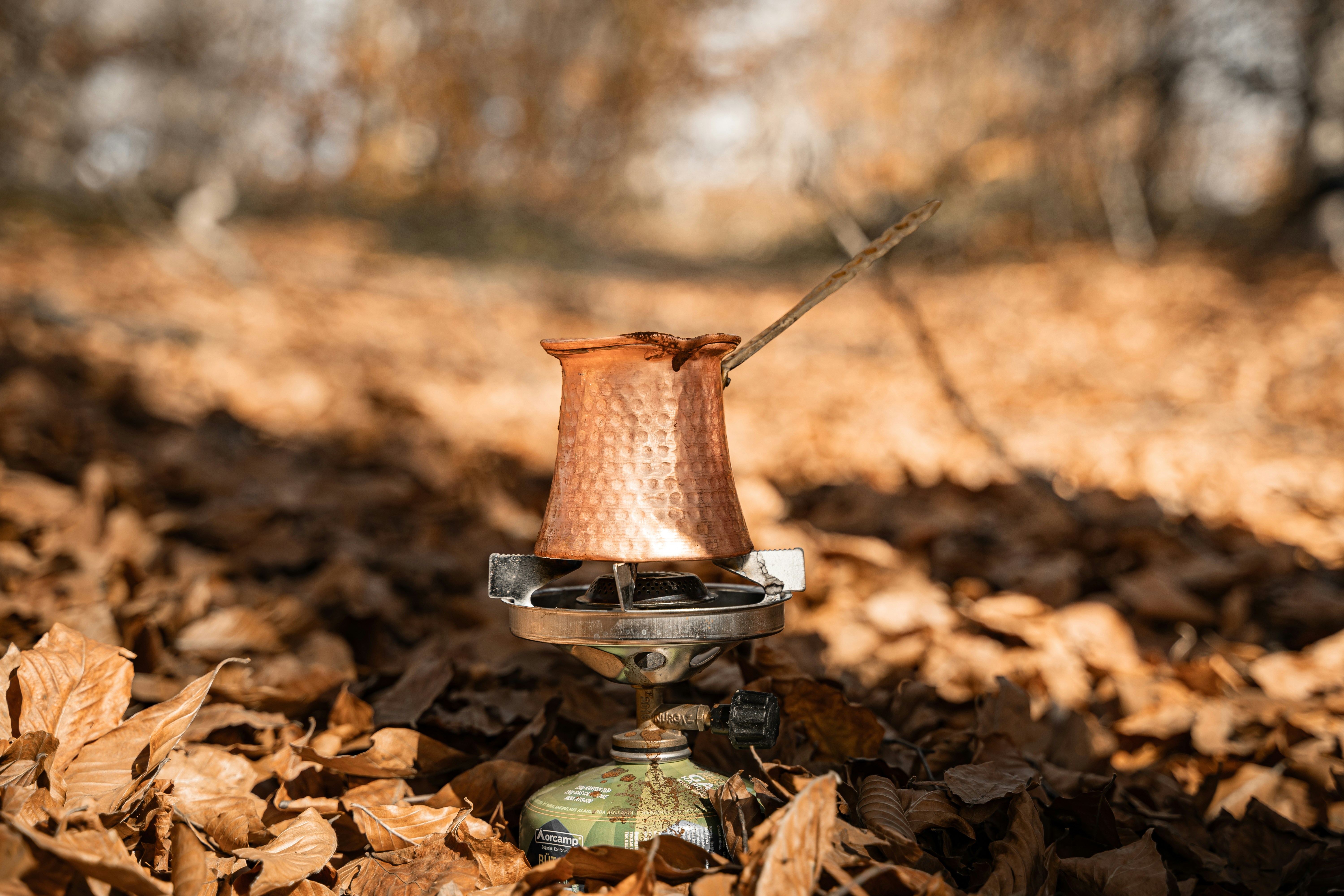 Copper cezve brewing coffee on a portable stove outdoors
