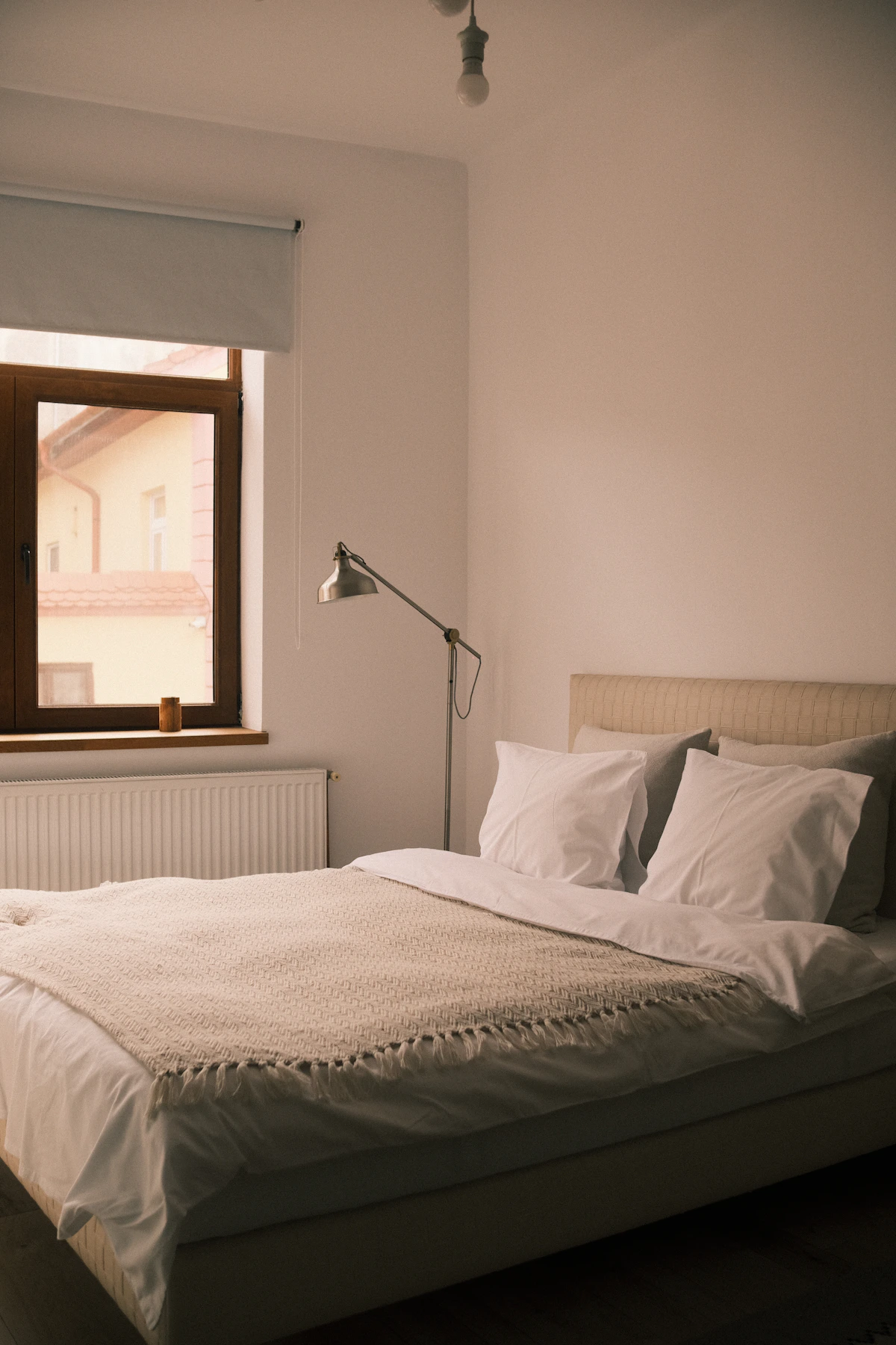 Calm minimalist bedroom with neutral bedding, soft blankets and gentle morning light