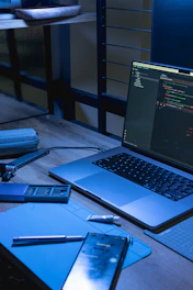 Laptop and phone on a desk with coding software open.