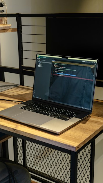 Laptop terbuka di atas meja kayu menampilkan layar kode, cocok untuk tutorial ZCode AI coding workspace