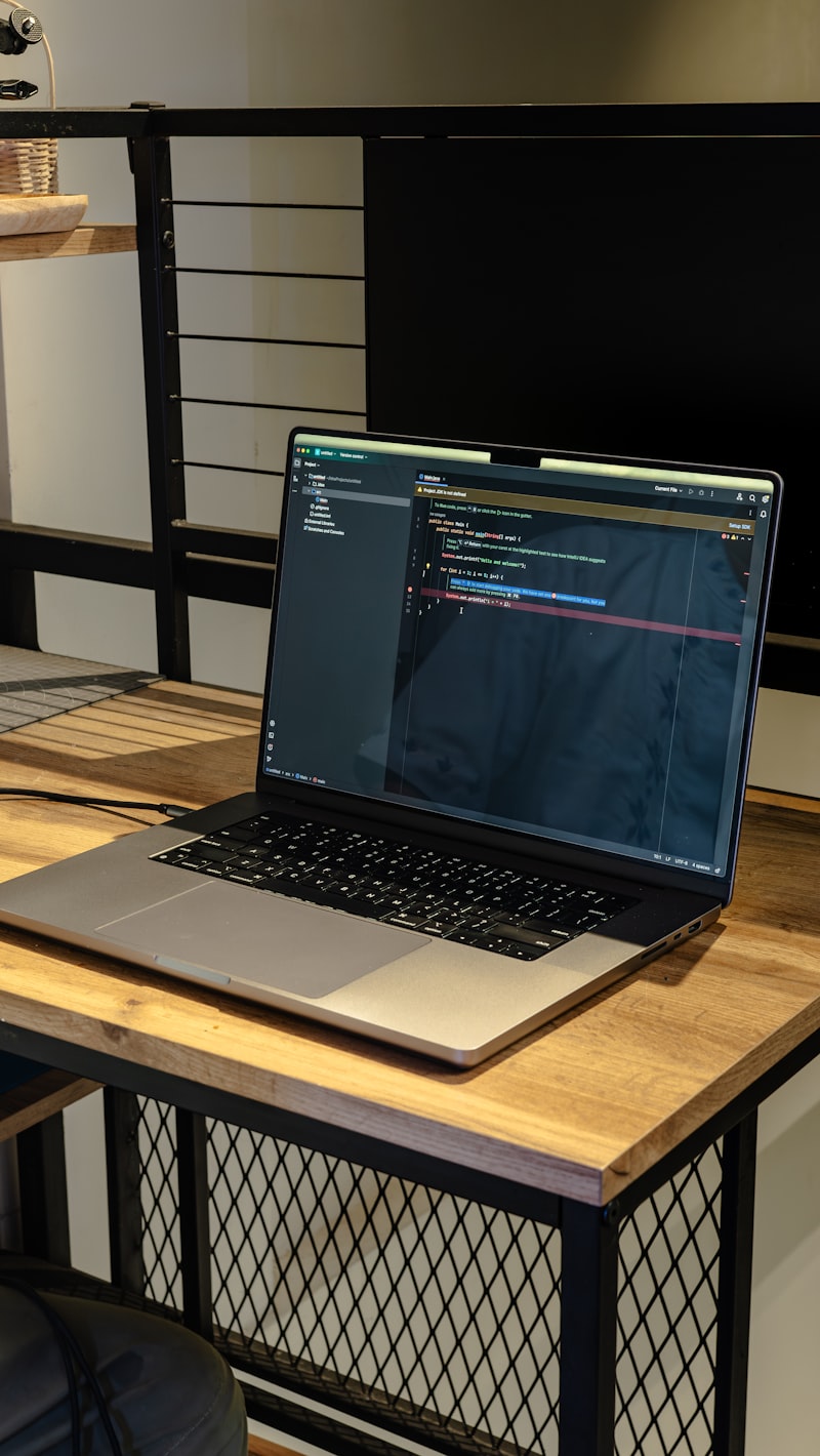 Offener Laptop mit Code auf dem Bildschirm auf einem Holztisch