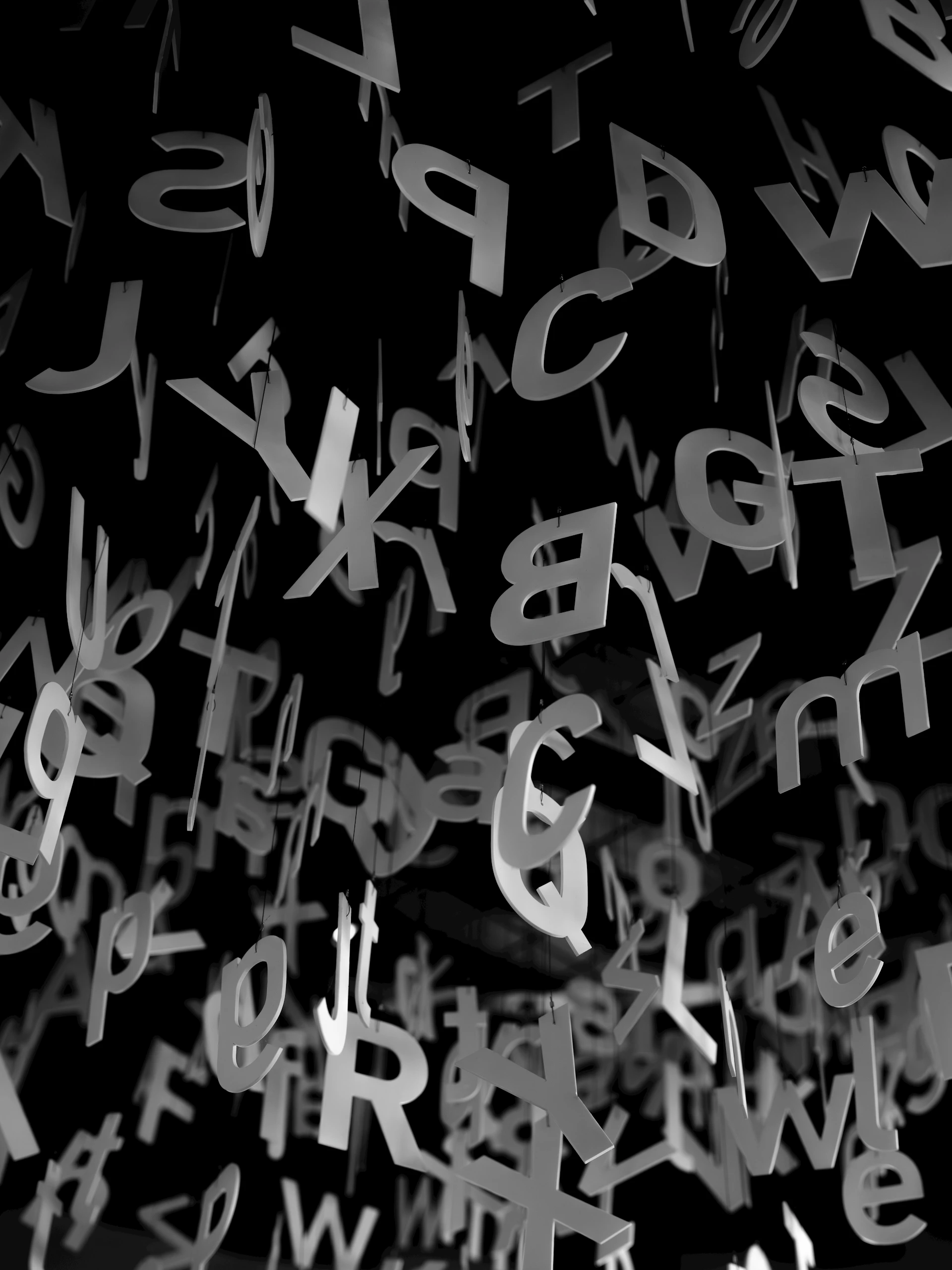 Many letters of the alphabet hanging against a black background.