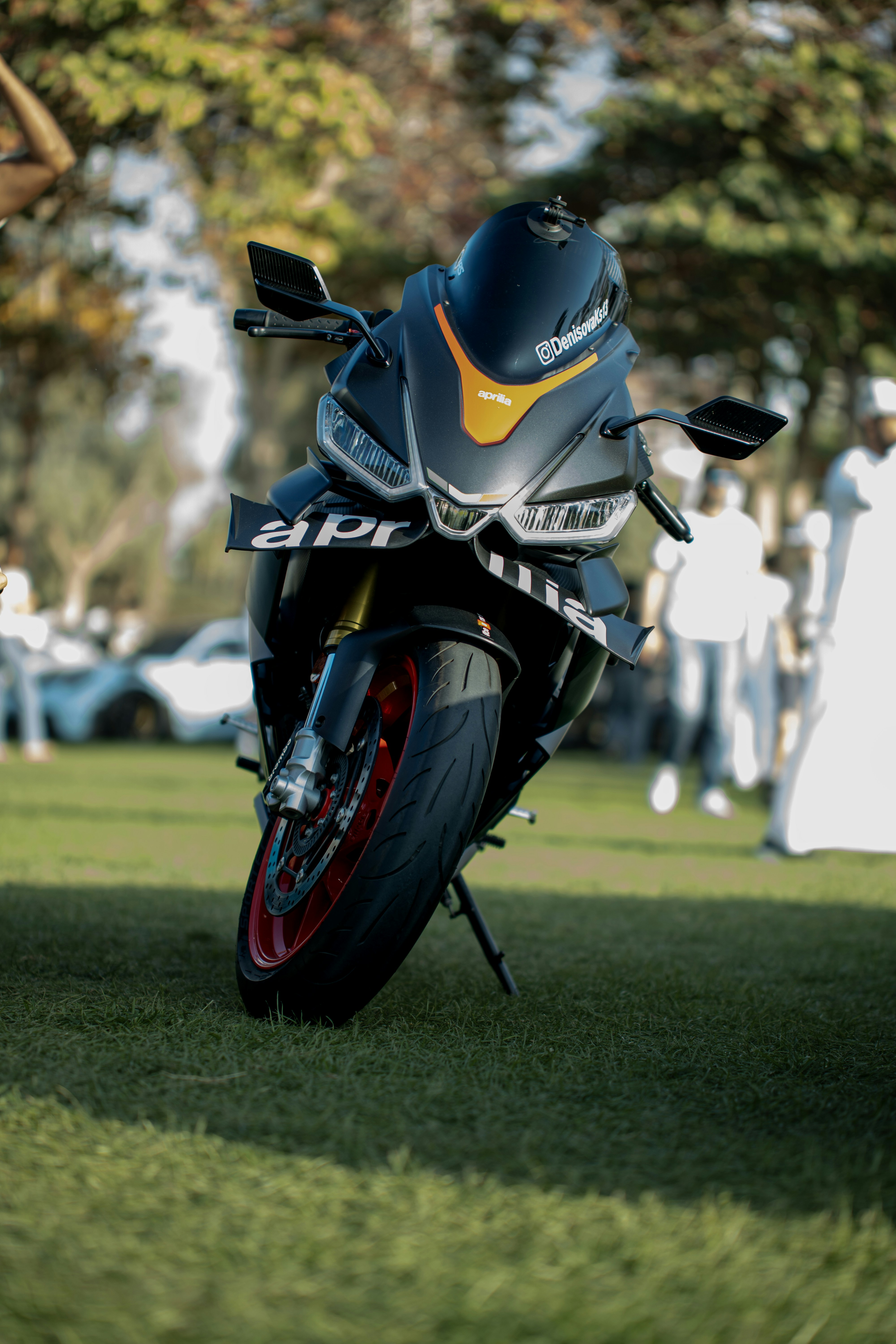 Sebuah sepeda motor sport hitam dan kuning diparkir di rumput.