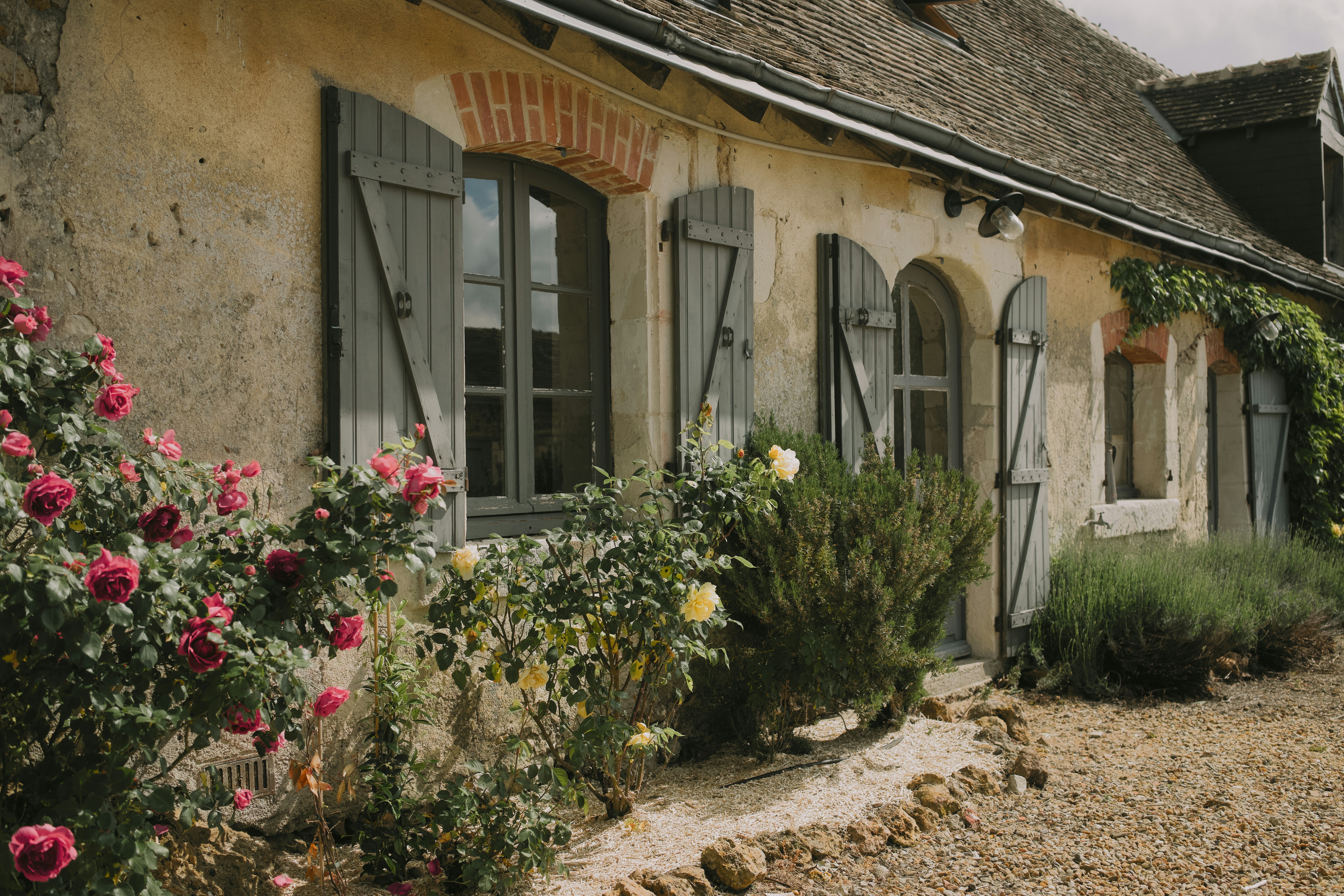 Encantadora casa de pedra com rosas e venezianas floridas