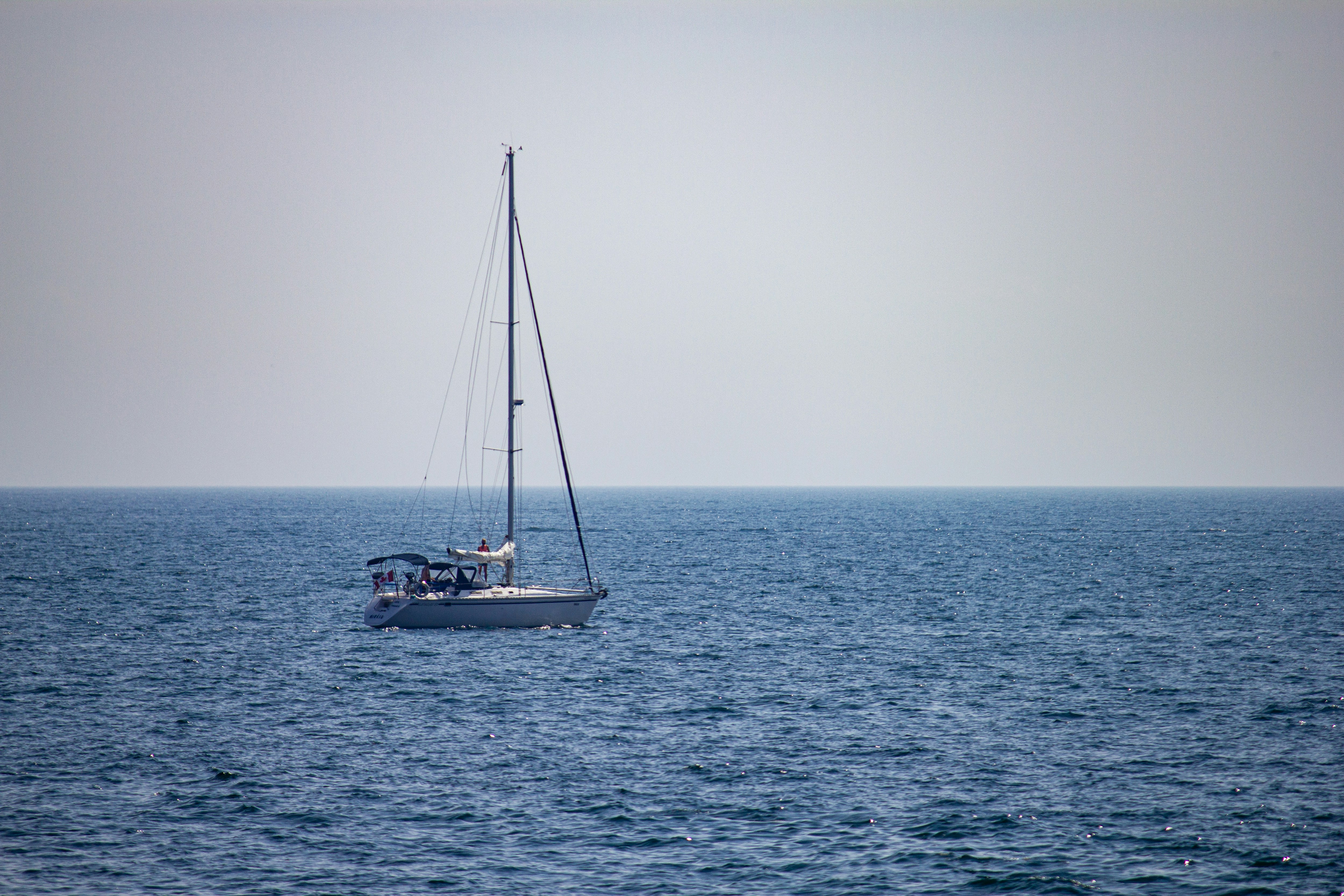 Un voilier solitaire dérive sur un océan bleu calme.