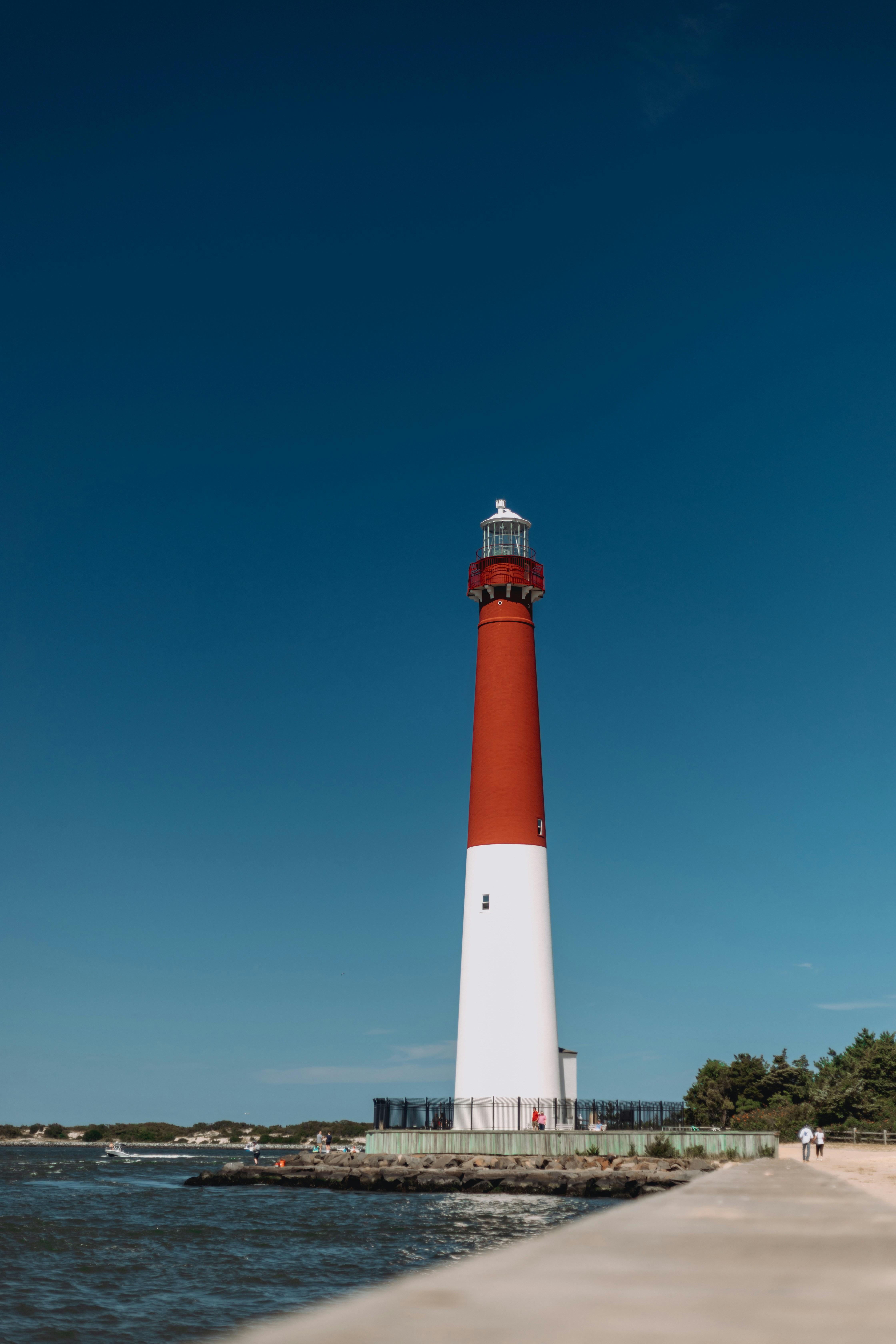 Un grand phare rouge et blanc se dresse au bord de l’océan.