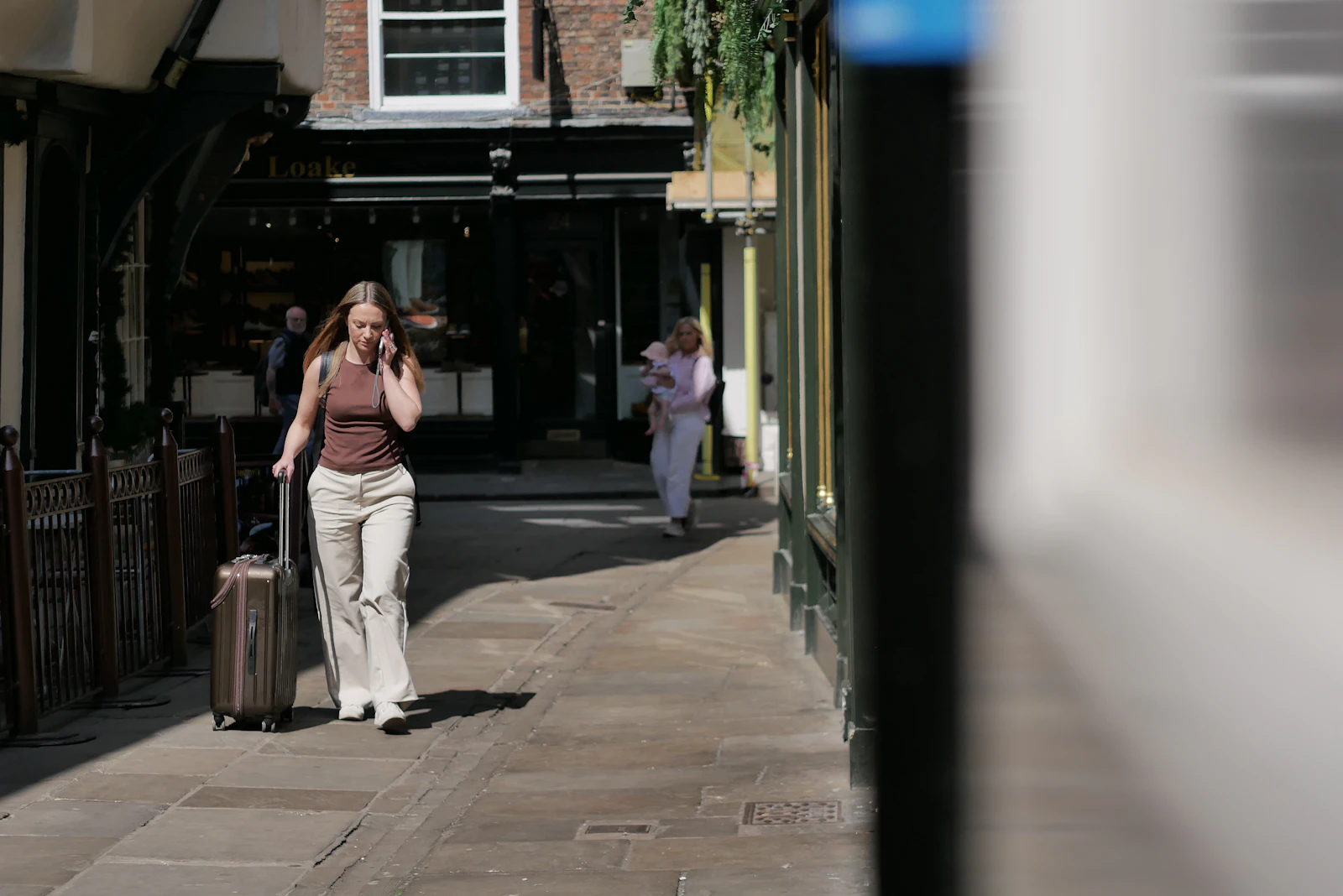 Woman walking alone with a suitcase on a cobblestone street