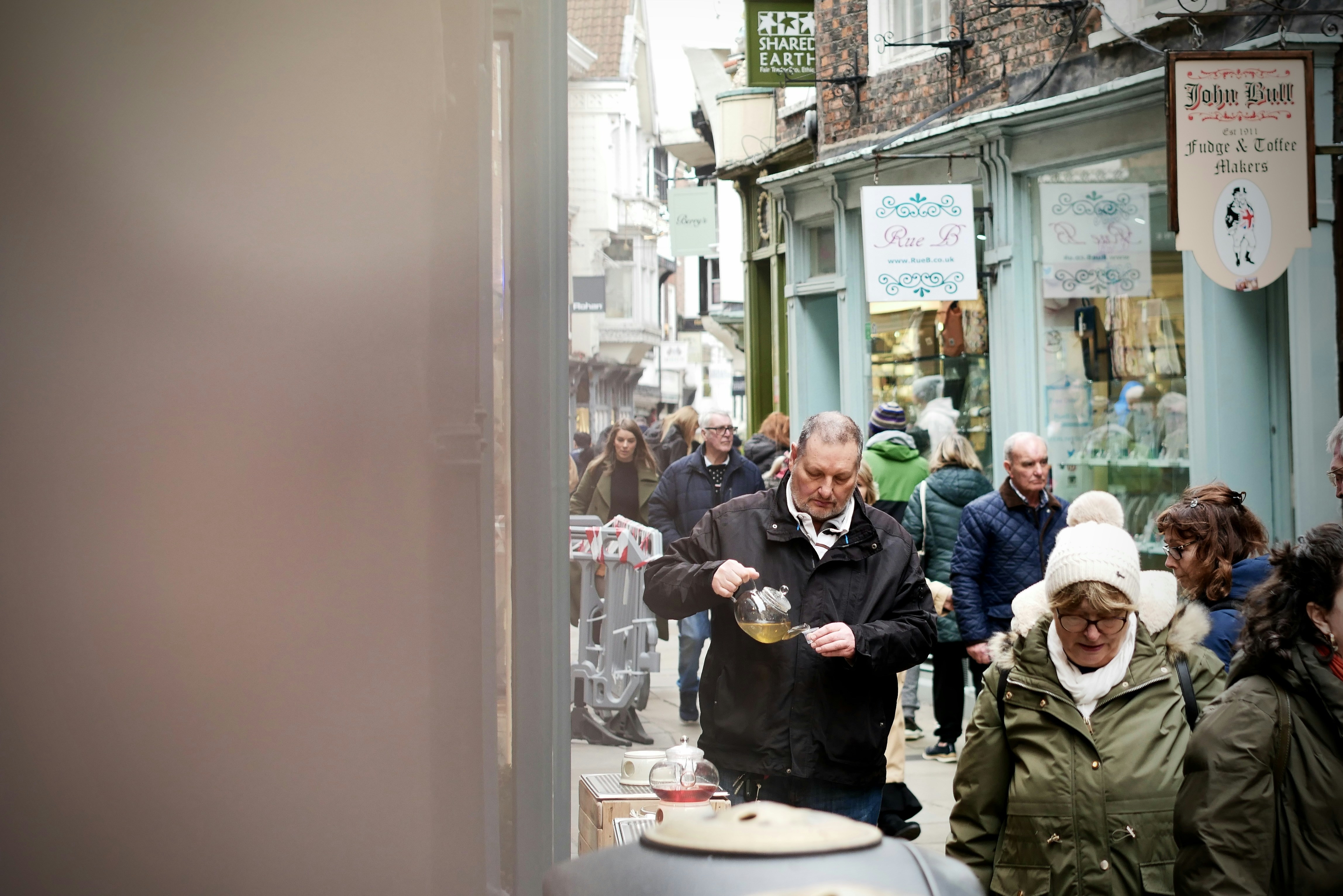People walking down a narrow street with shops.