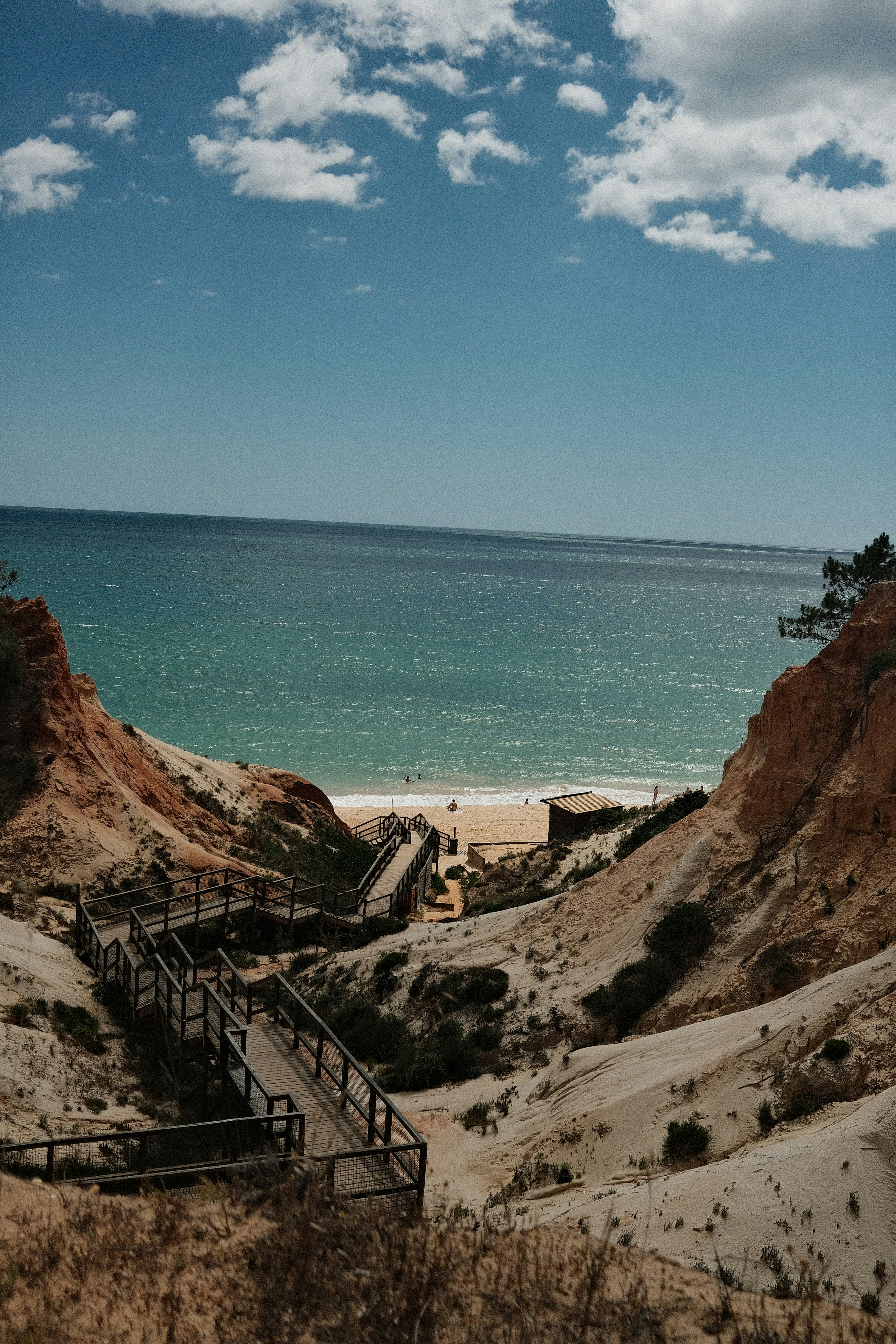 Wooden stairs lead down to a sandy beach and ocean.