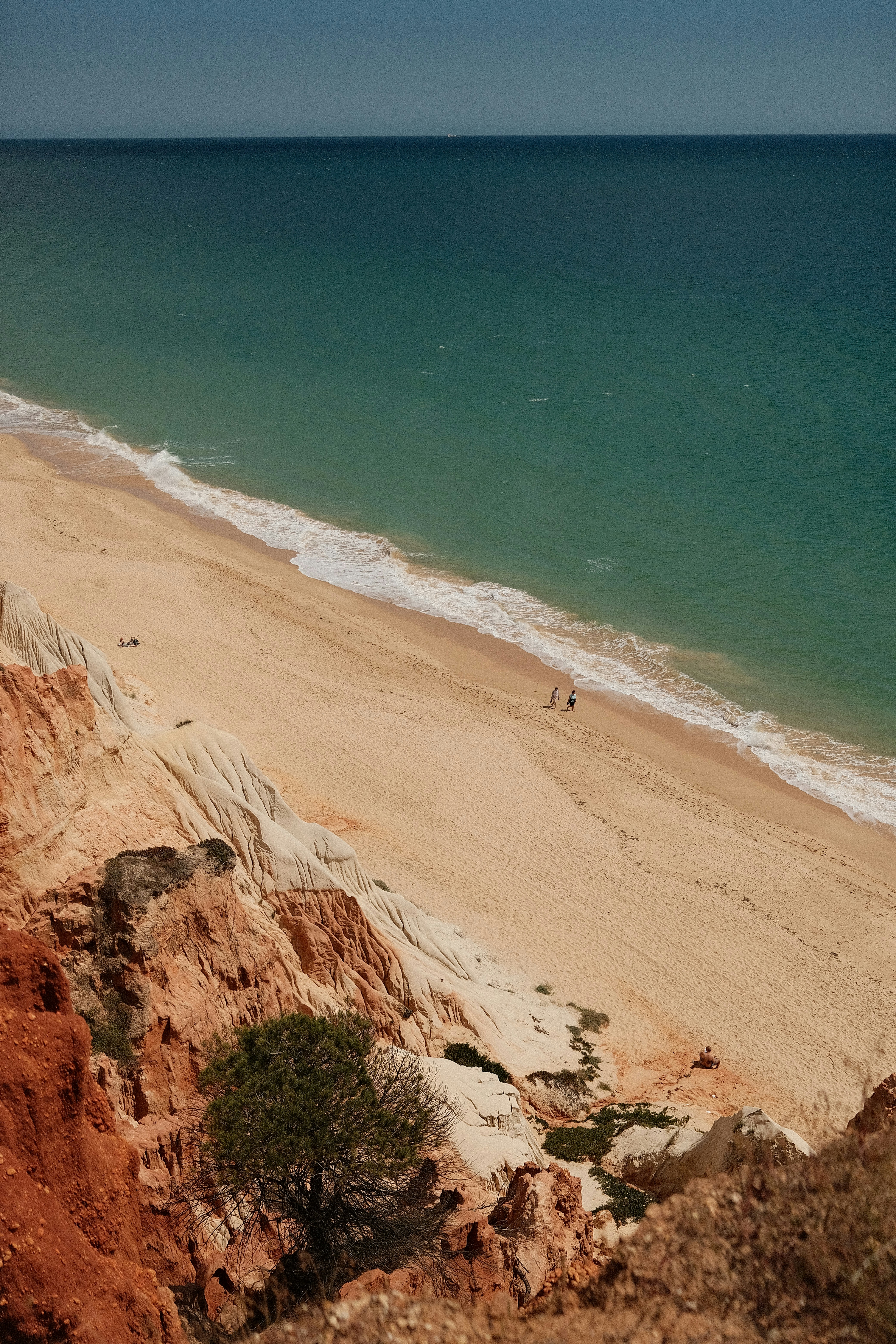 Sandy beach with colorful cliffs and turquoise ocean.