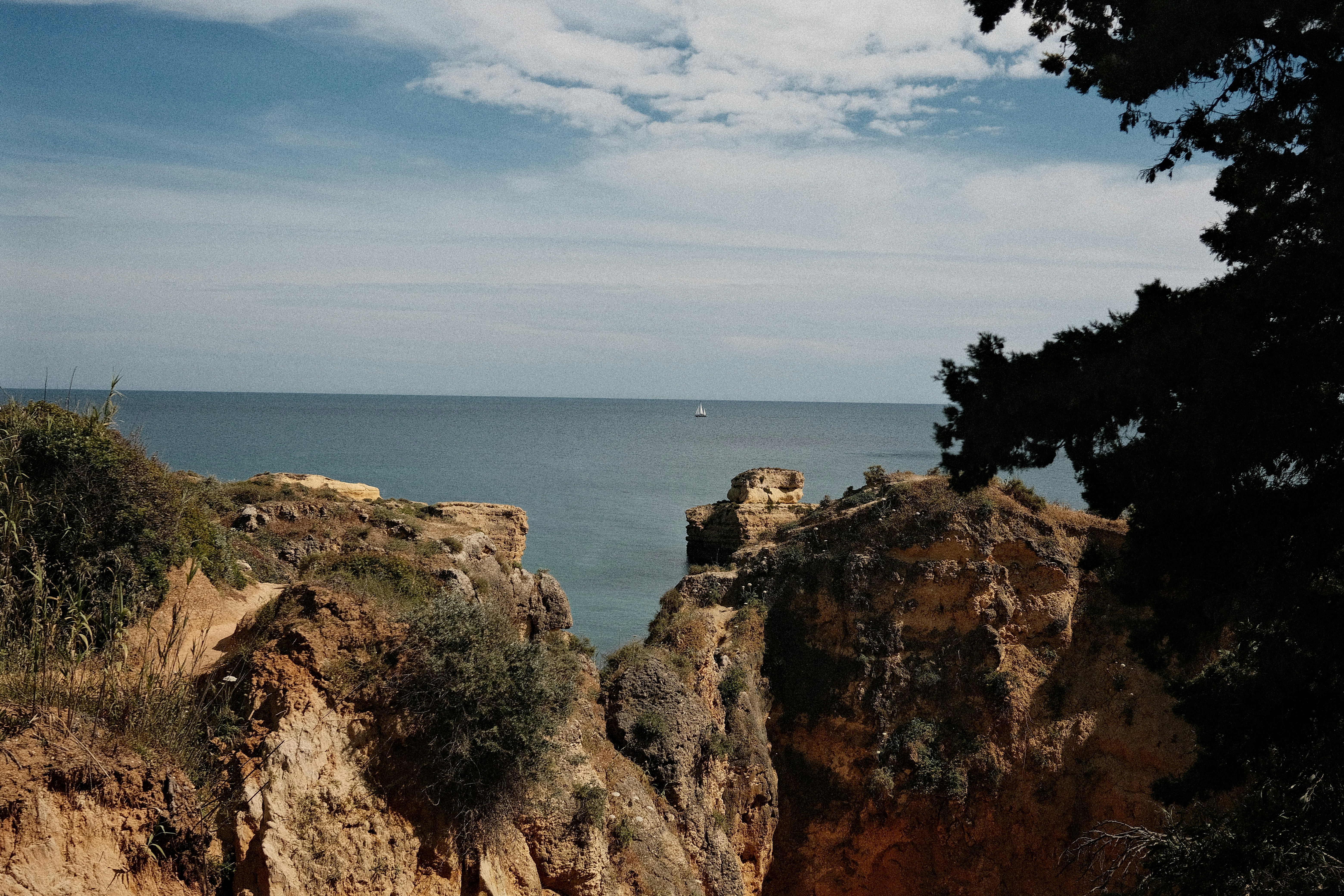 Rocky coastline overlooking the calm ocean under a cloudy sky.