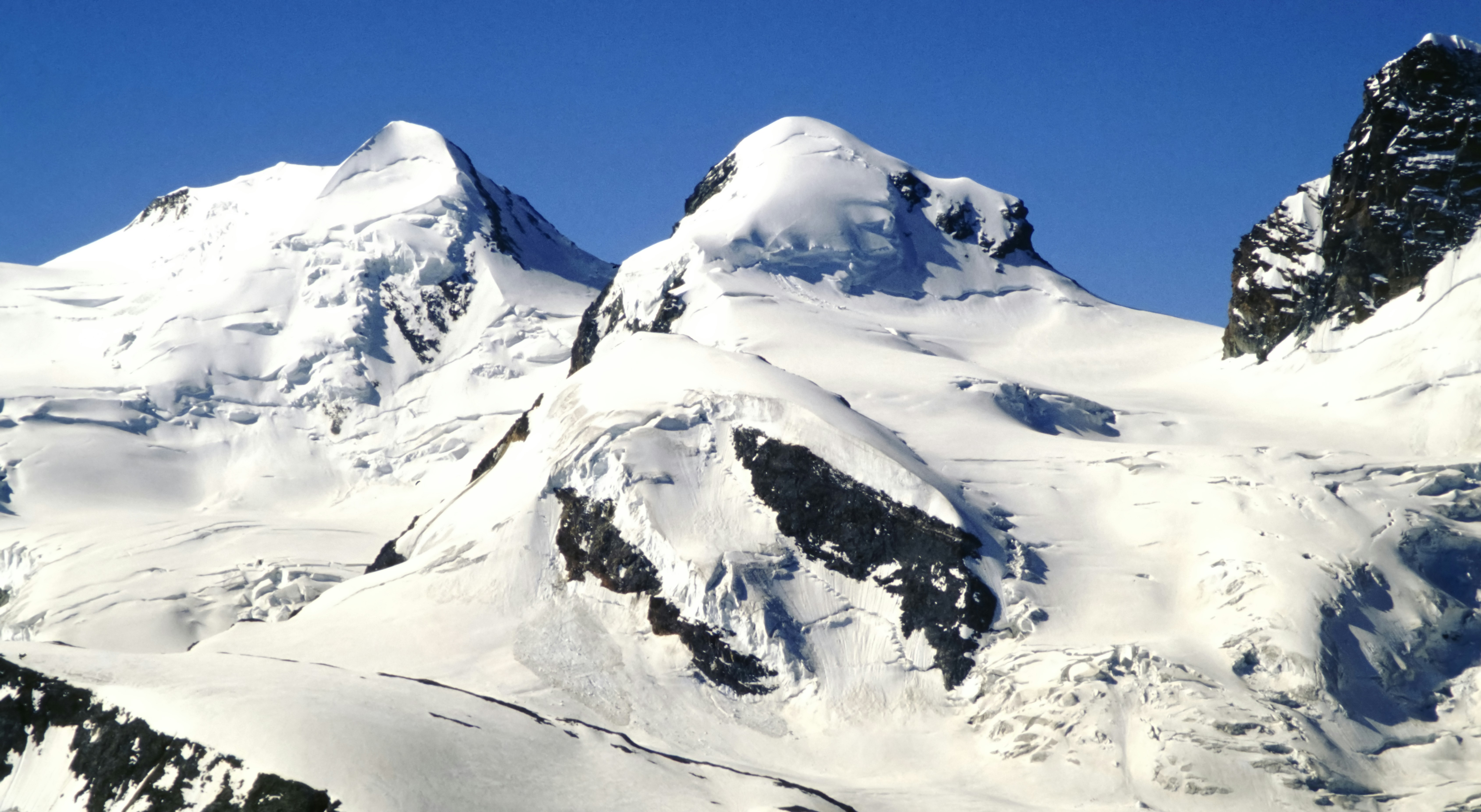 Picos de montanhas cobertos de neve sob um céu azul claro