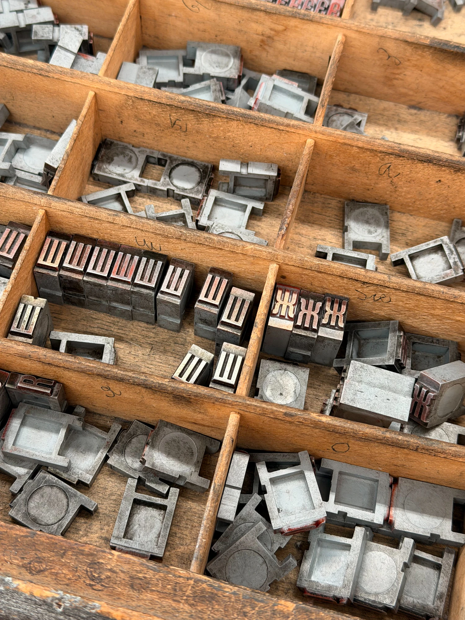 A printer's wooden type case seen from above, its compartments full of grey metal sorts