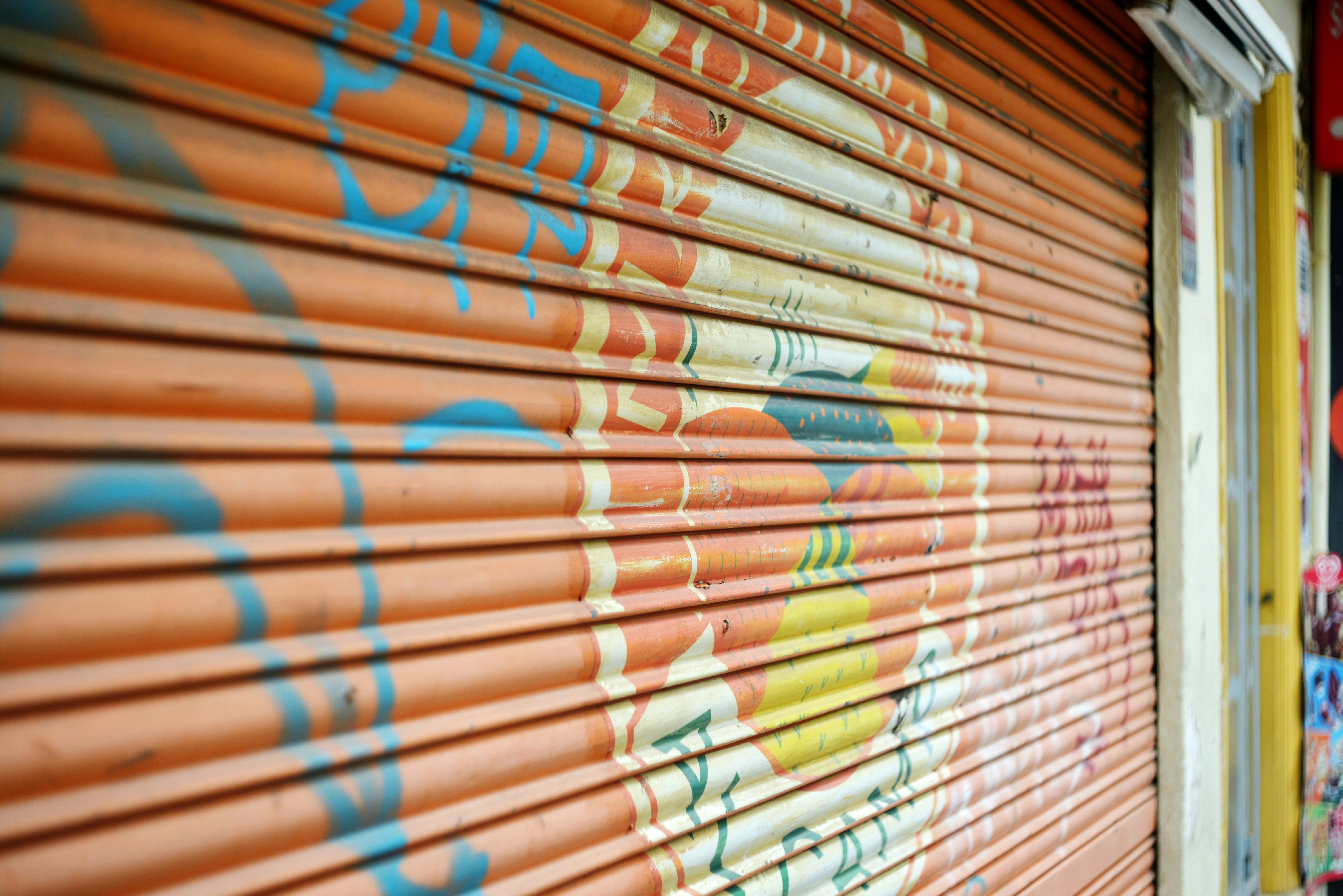 Orange metal security shutter with graffiti