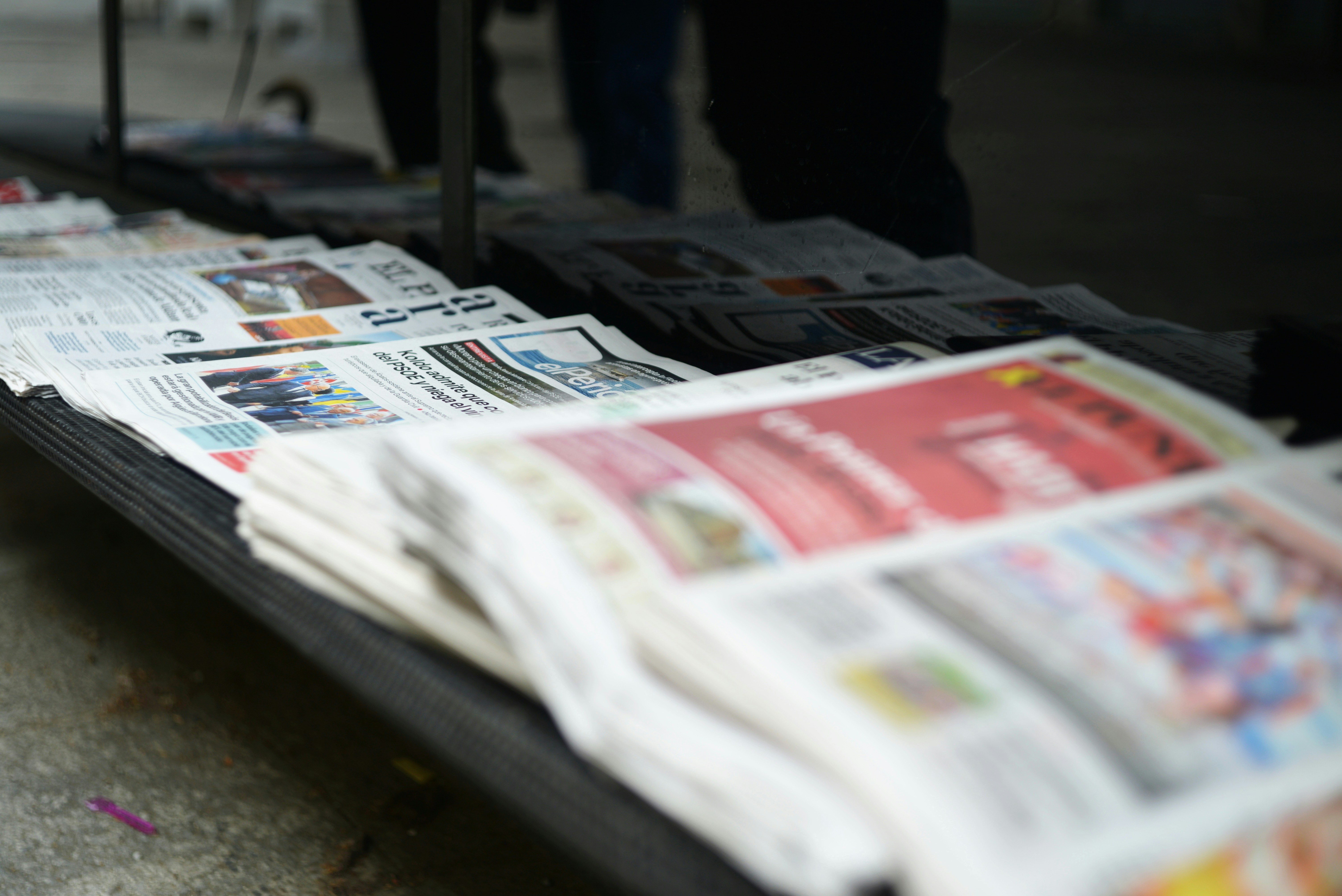 屋外のテーブルに新聞の山を置く。