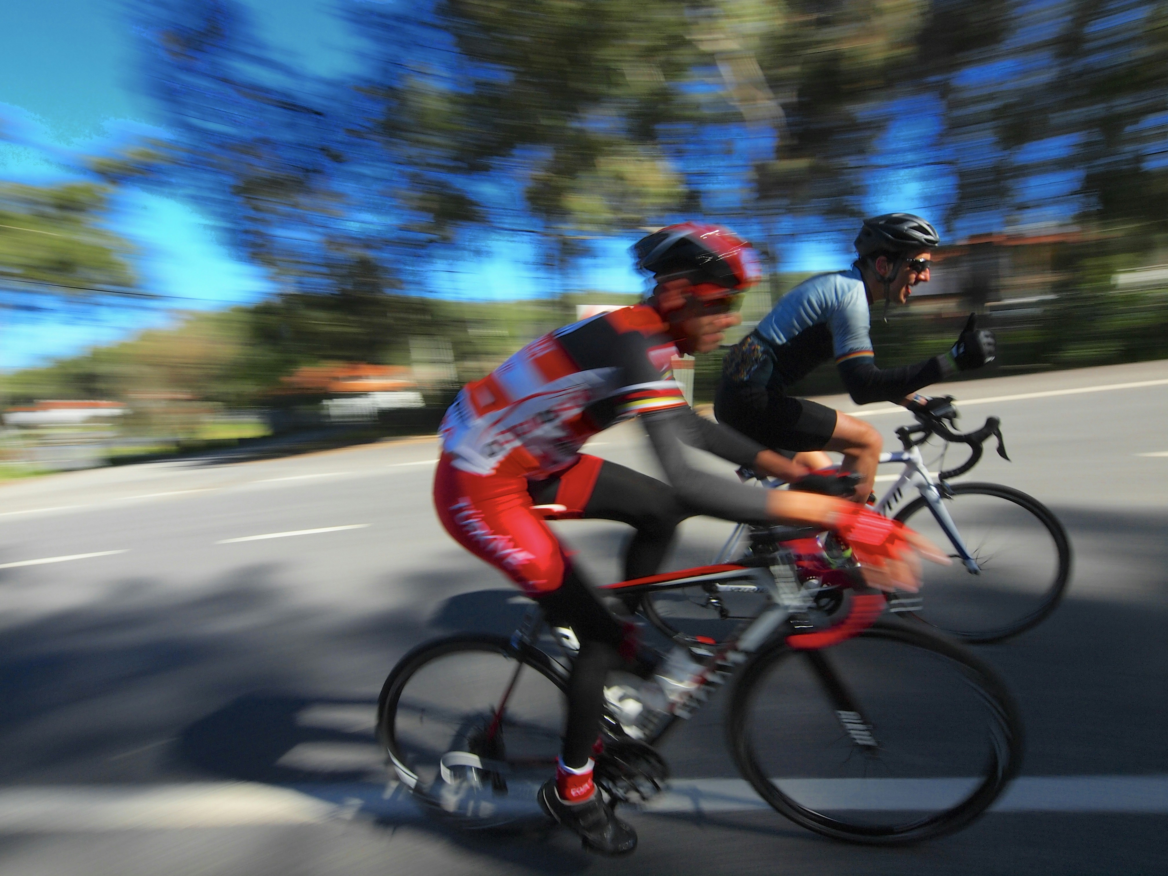 Two cyclists race down a road with motion blur