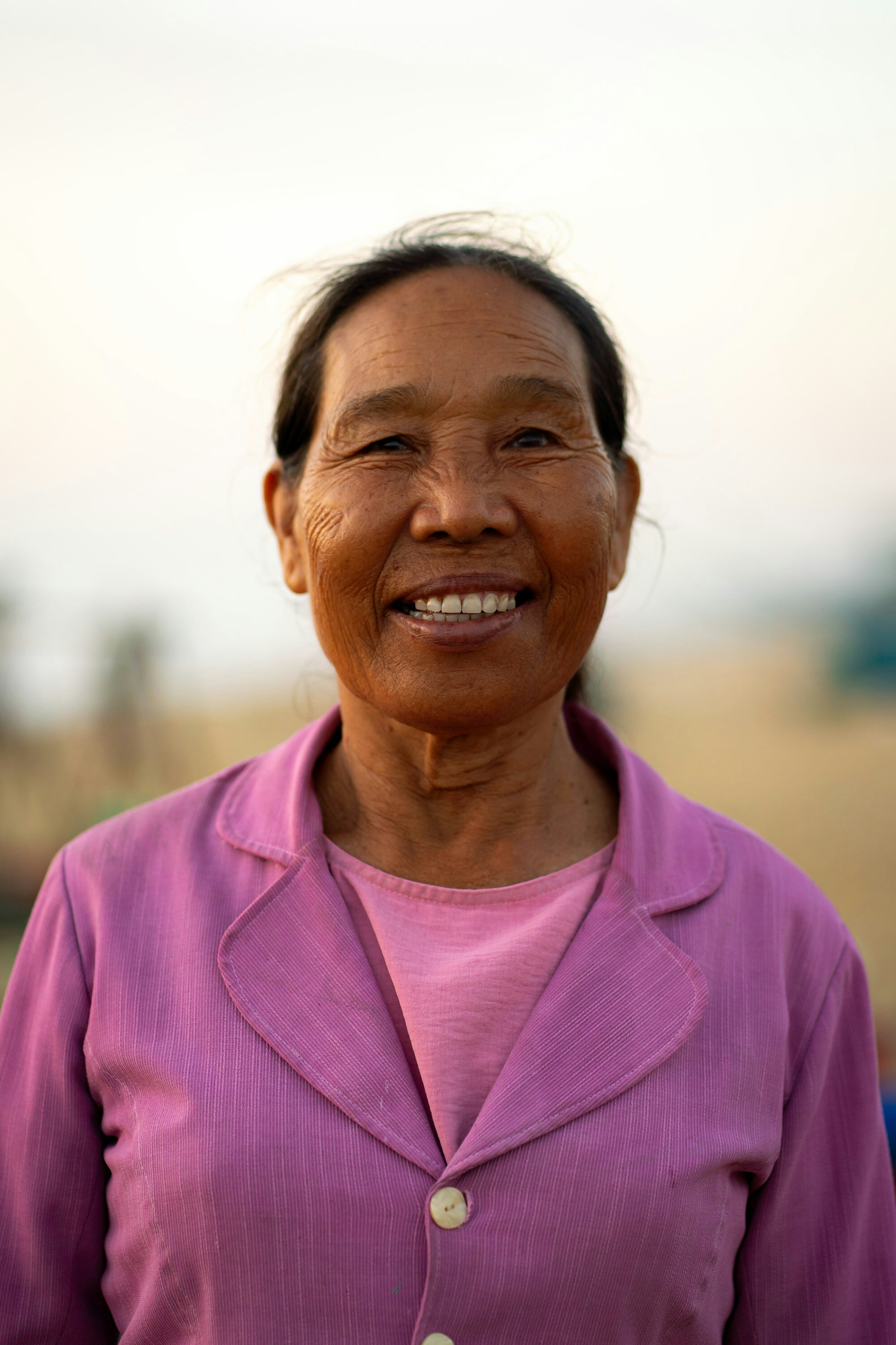 Elderly asian woman smiling in a purple jacket