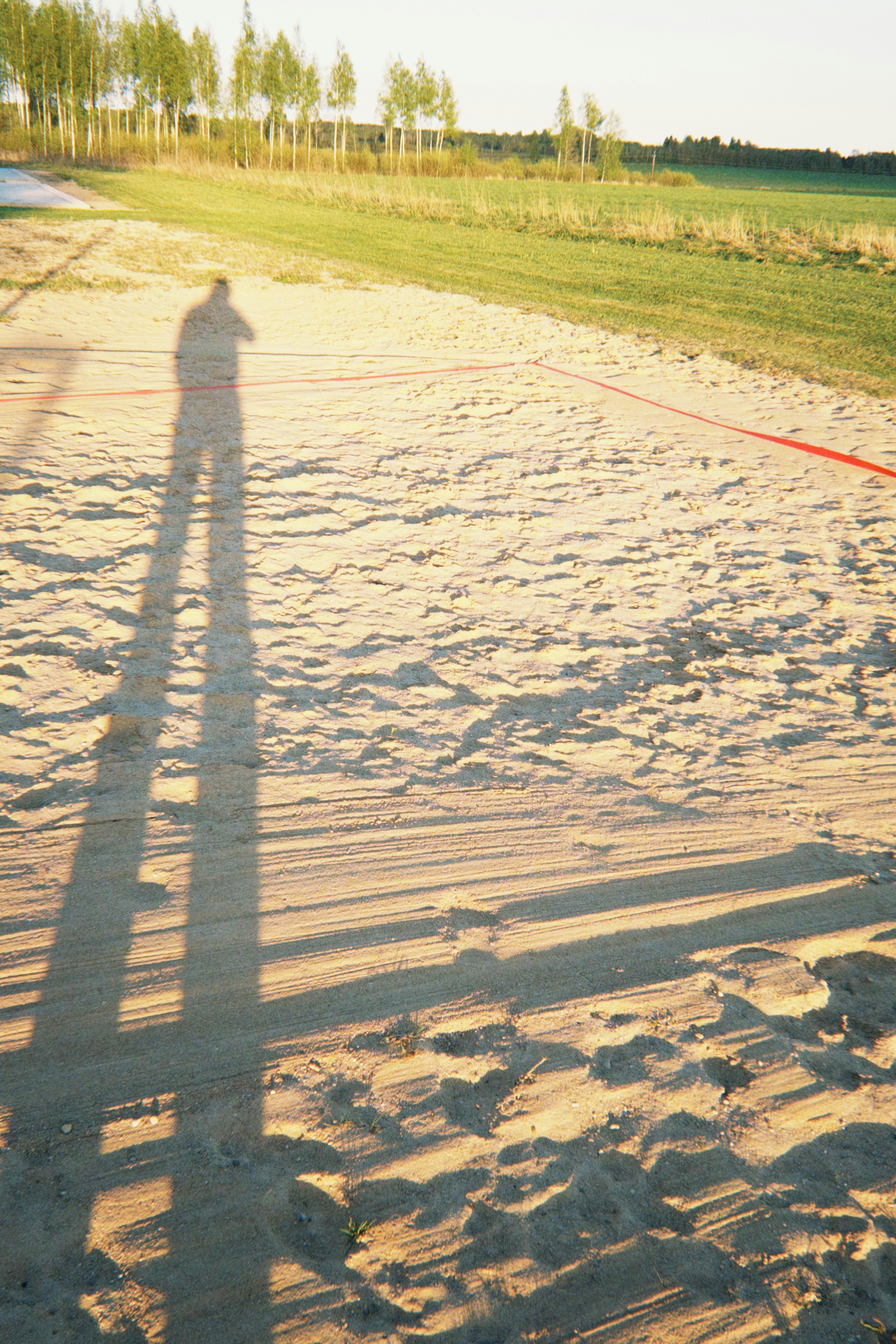 Long shadow of a person on sandy ground