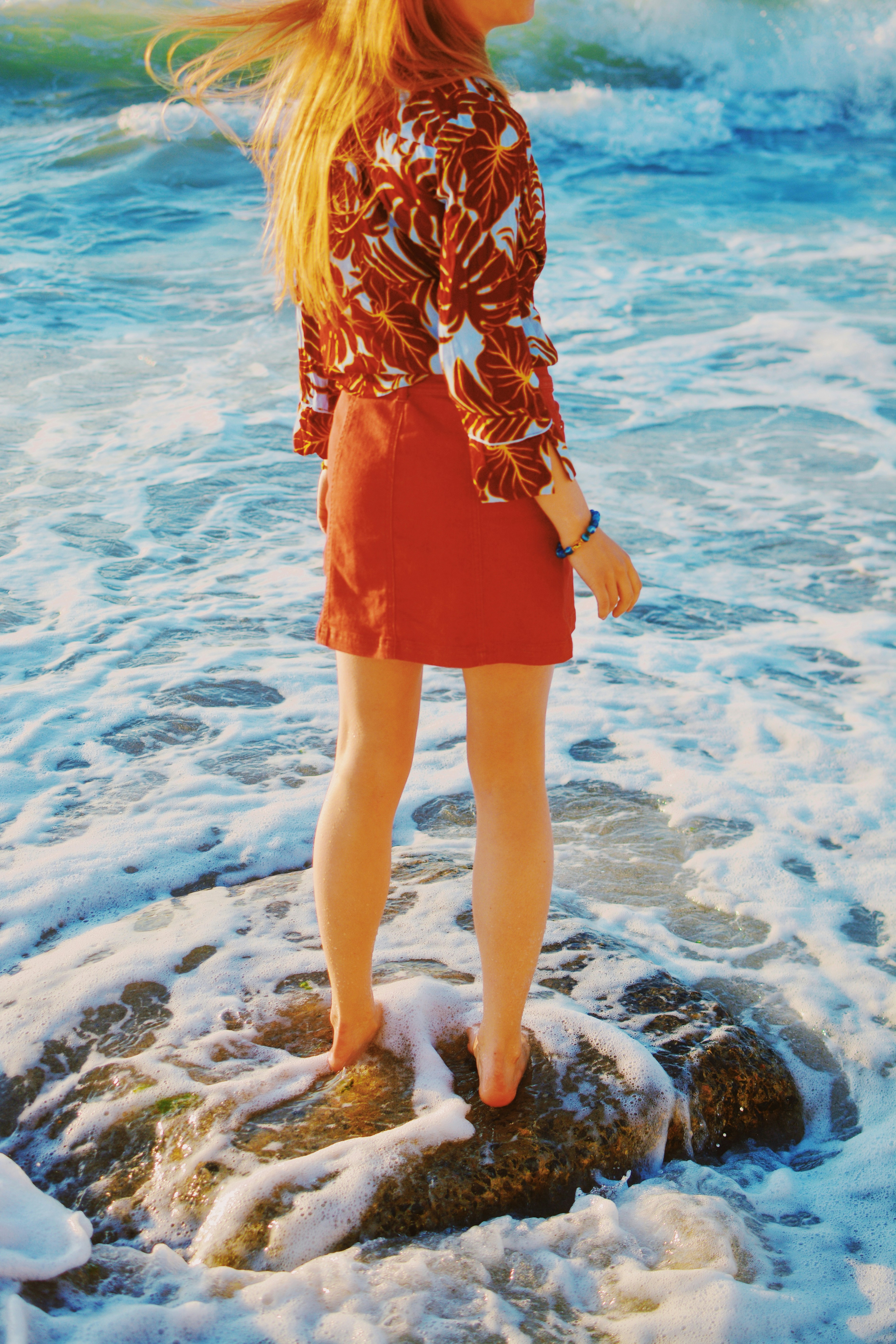 Woman standing on rock in ocean waves