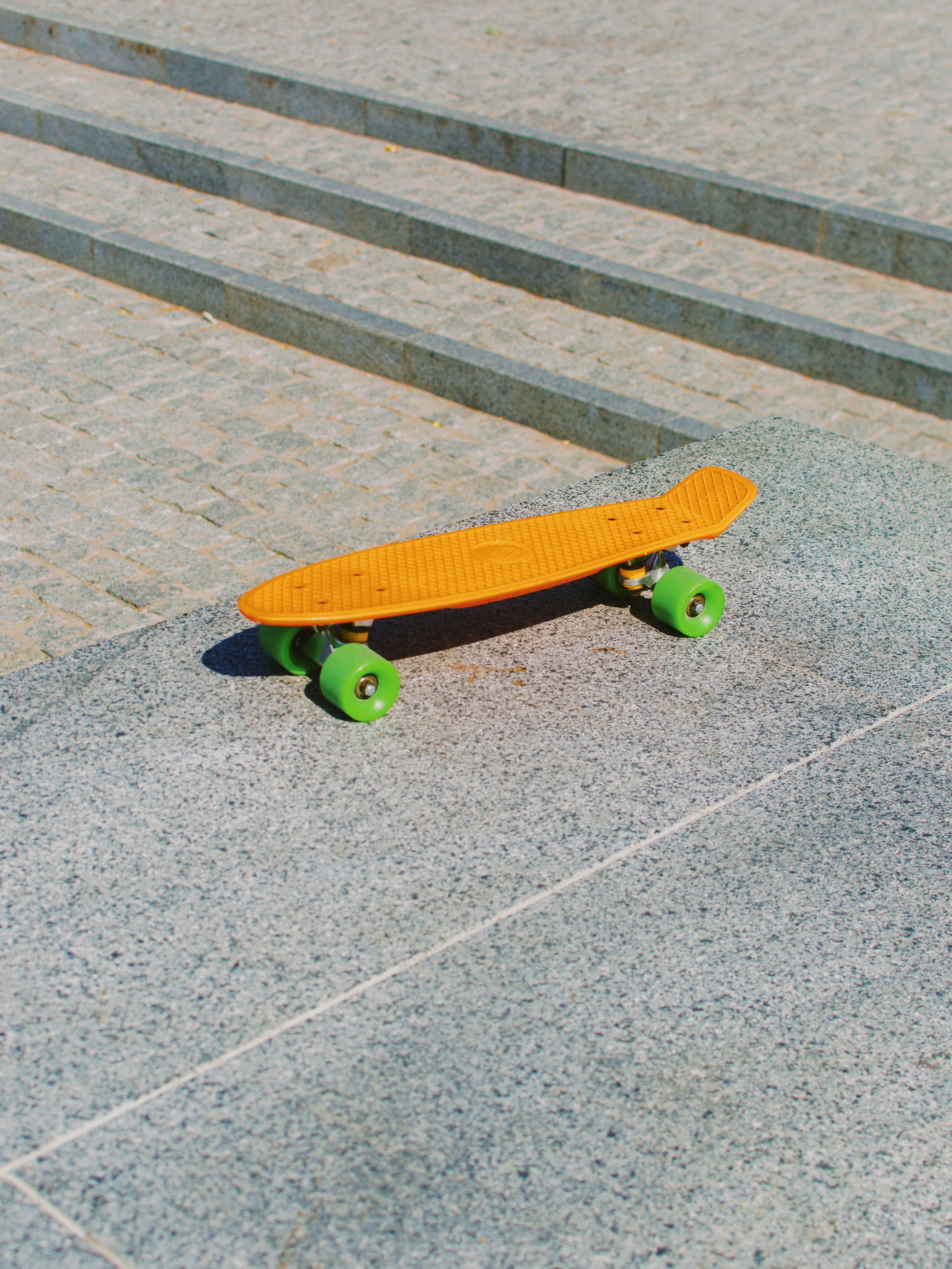 Orange skateboard with green wheels on stairs