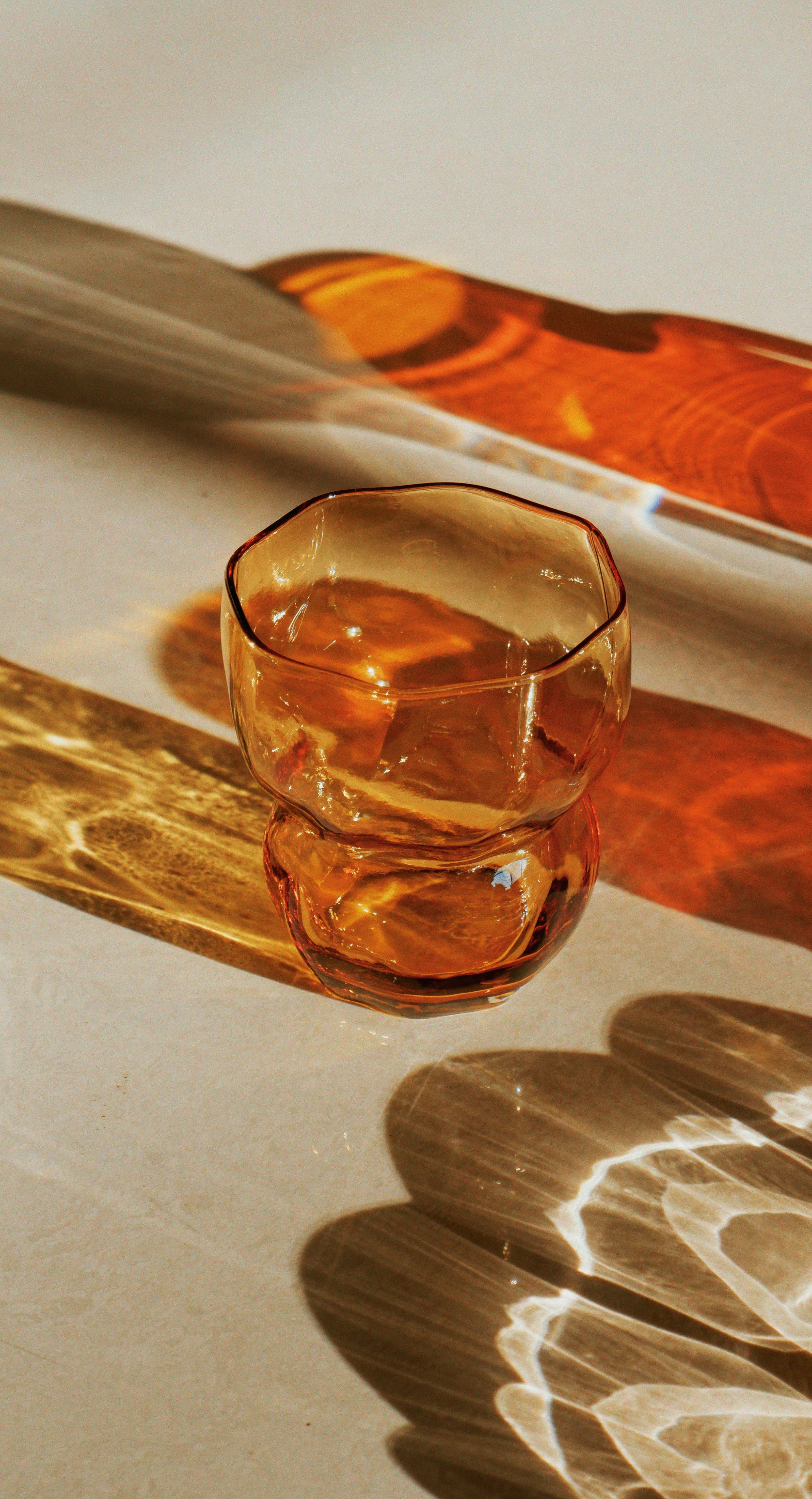 Bernsteinfarbener Glasbecher mit dramatischen Licht- und Schattenmustern