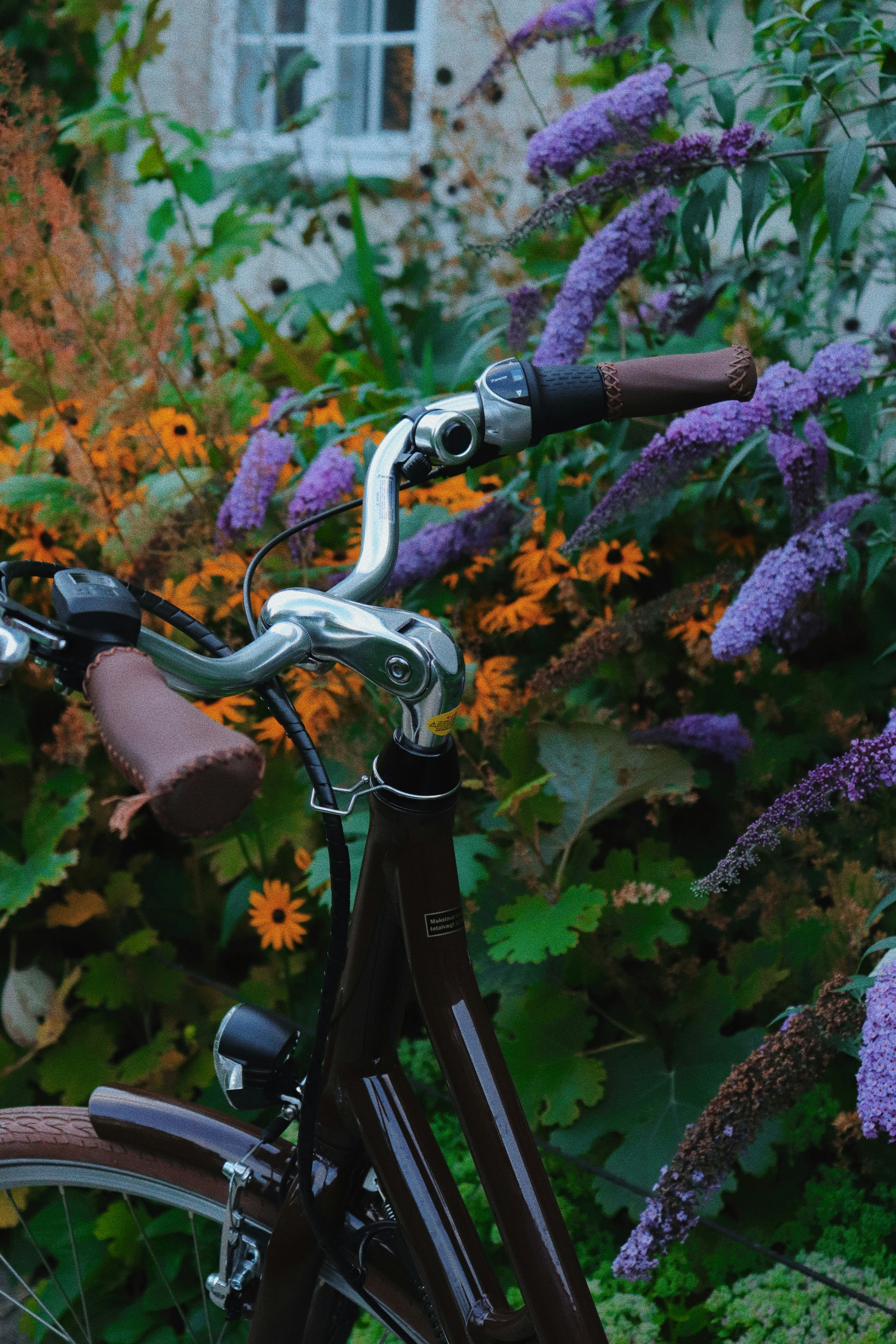 A bicycle parked in a garden with flowers.
