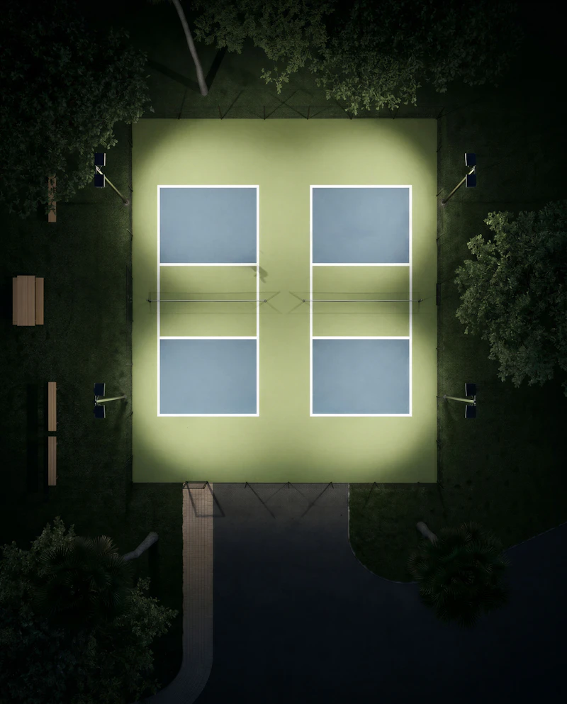 Illuminated pickleball courts at night, seen from above