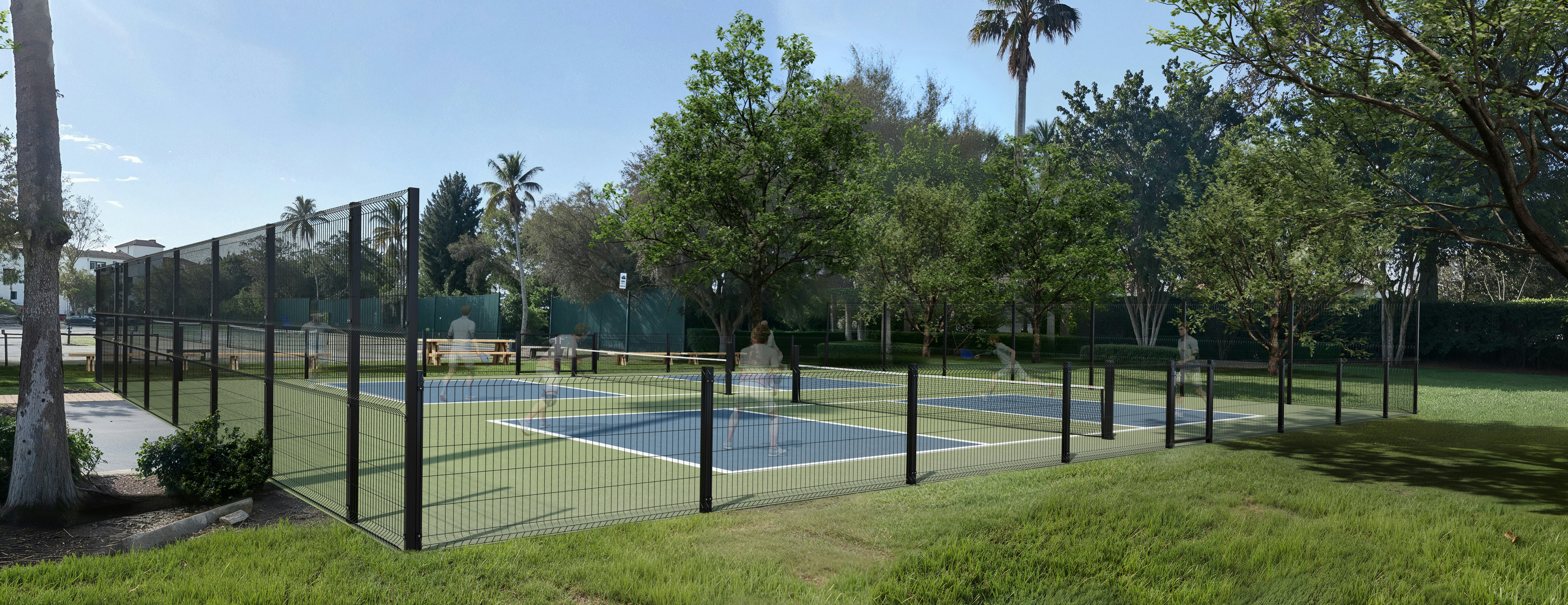 Freiluft-Pickleball-Plätze, umgeben von Bäumen und Gras.