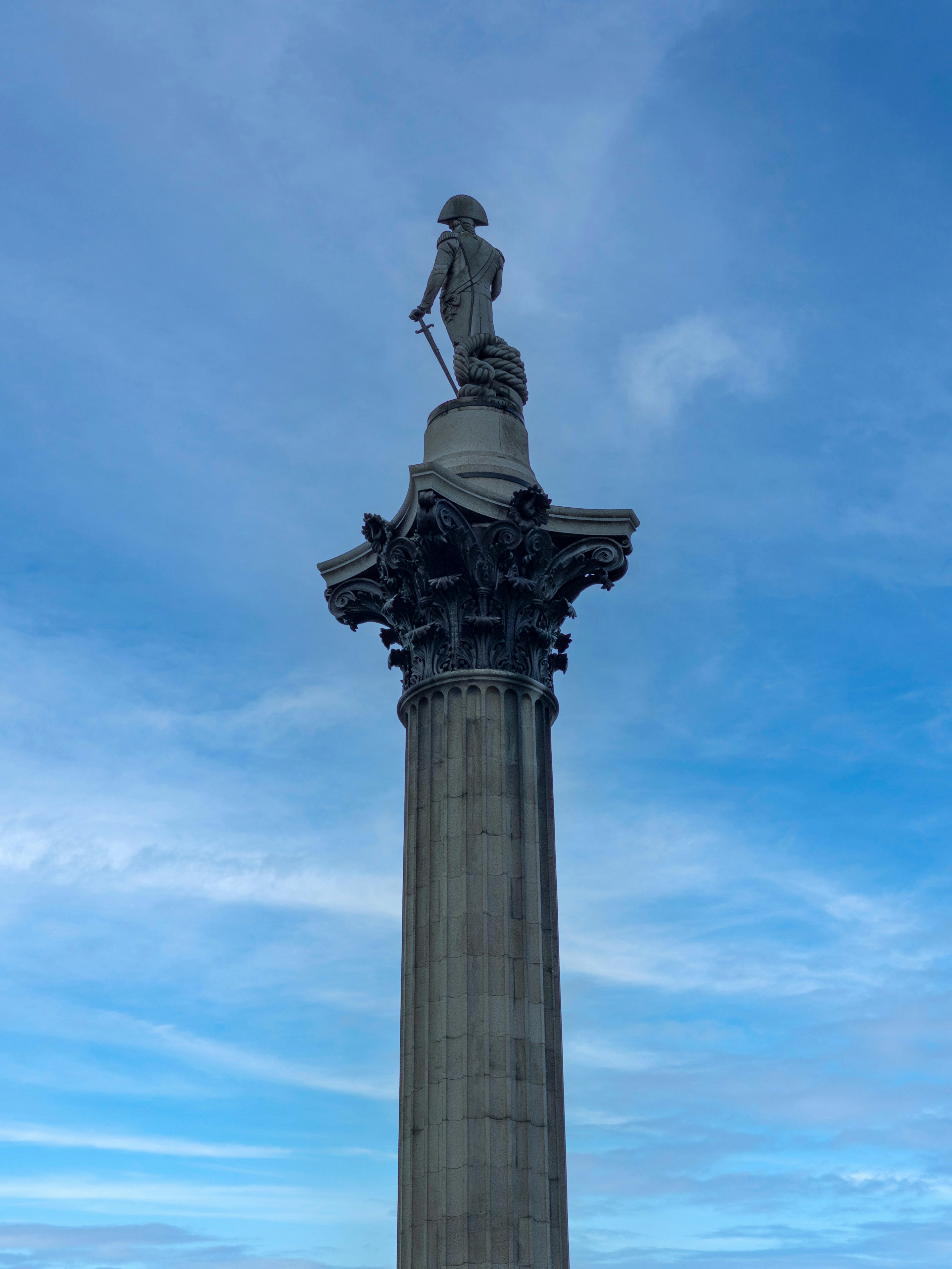 Nelson's column stands tall against a cloudy blue sky.