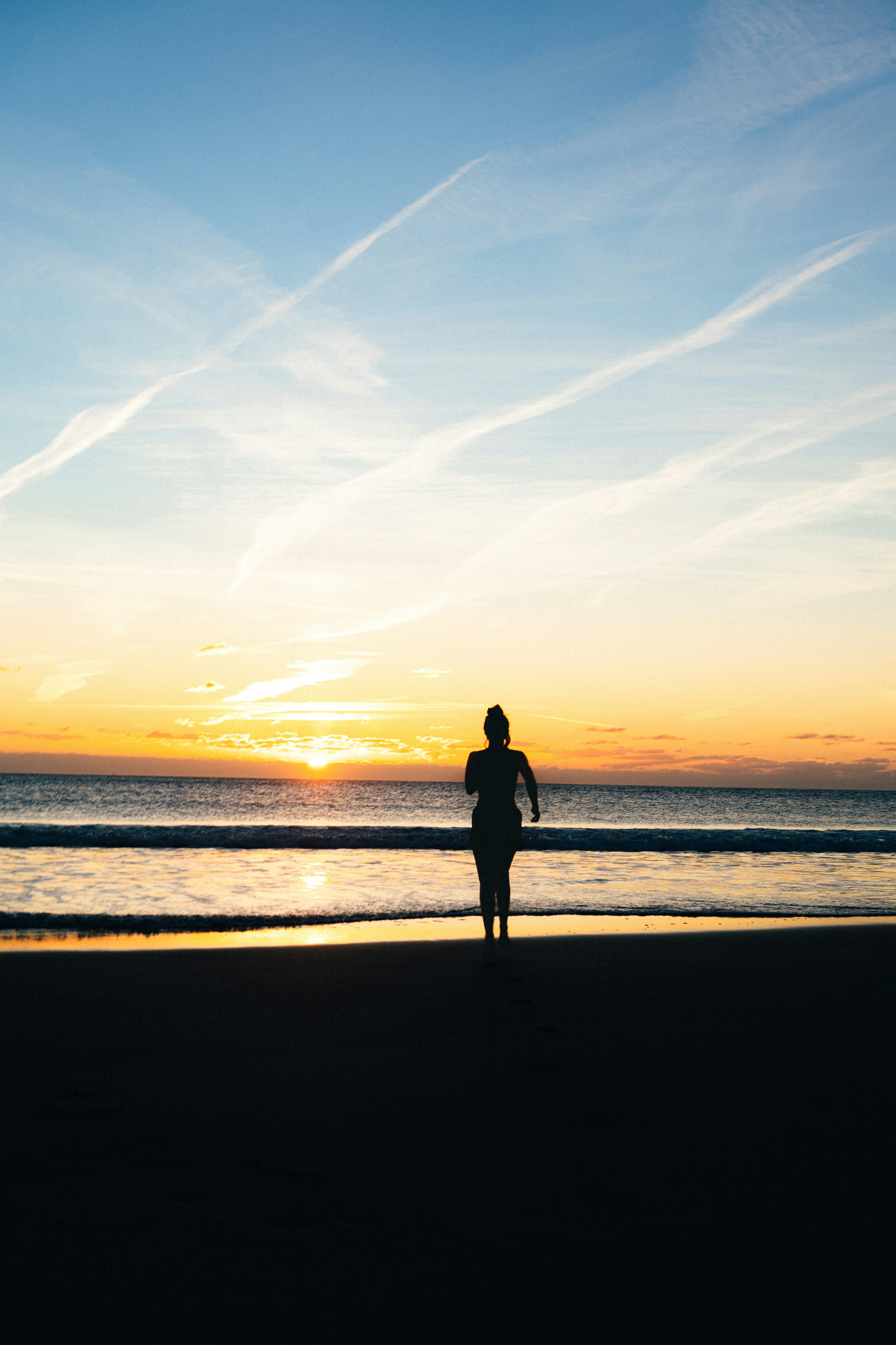 Woman running on beach at sunset