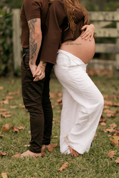 Couple holding hands, woman showing pregnant belly.