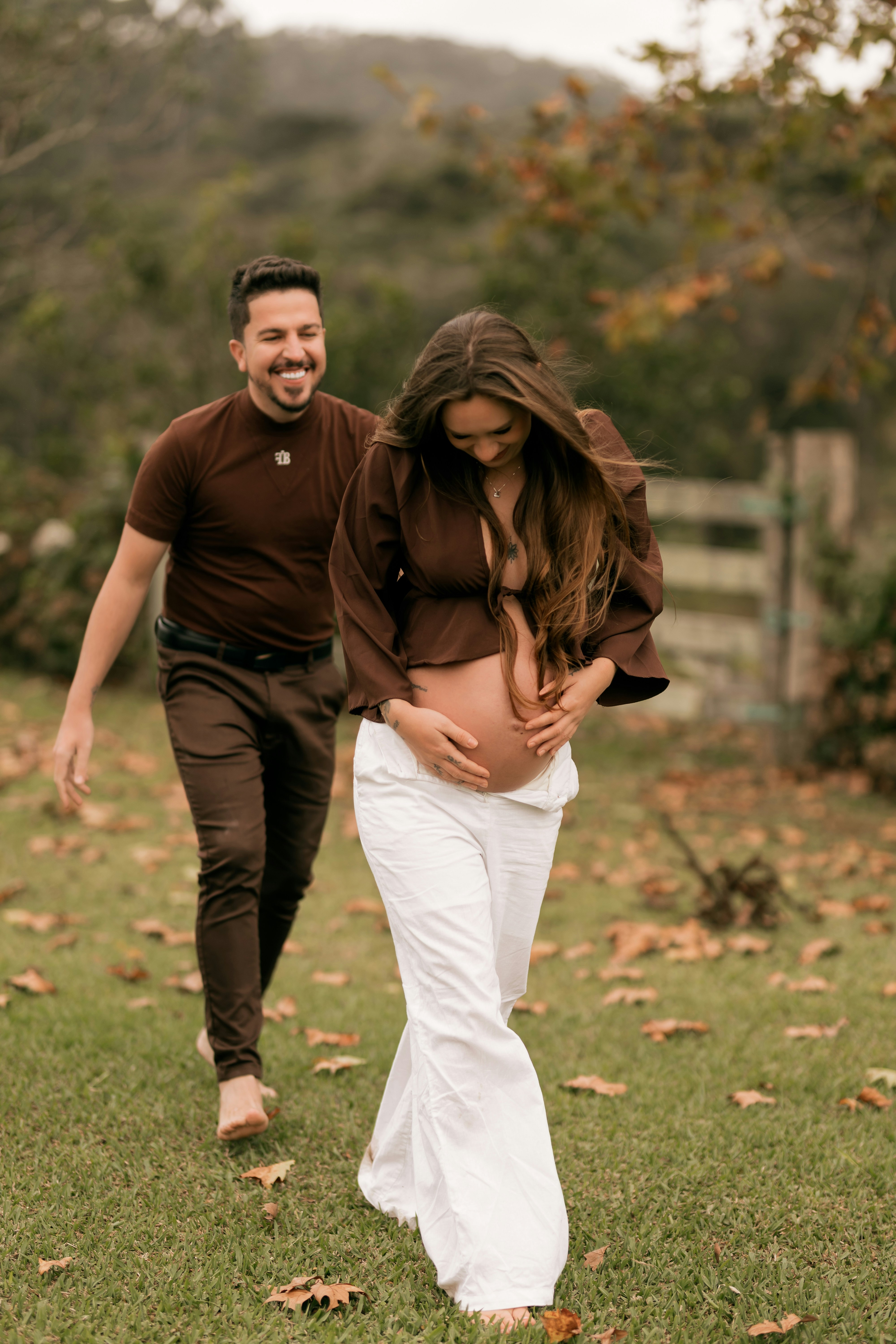 妊婦のカップルが草原を歩いている。