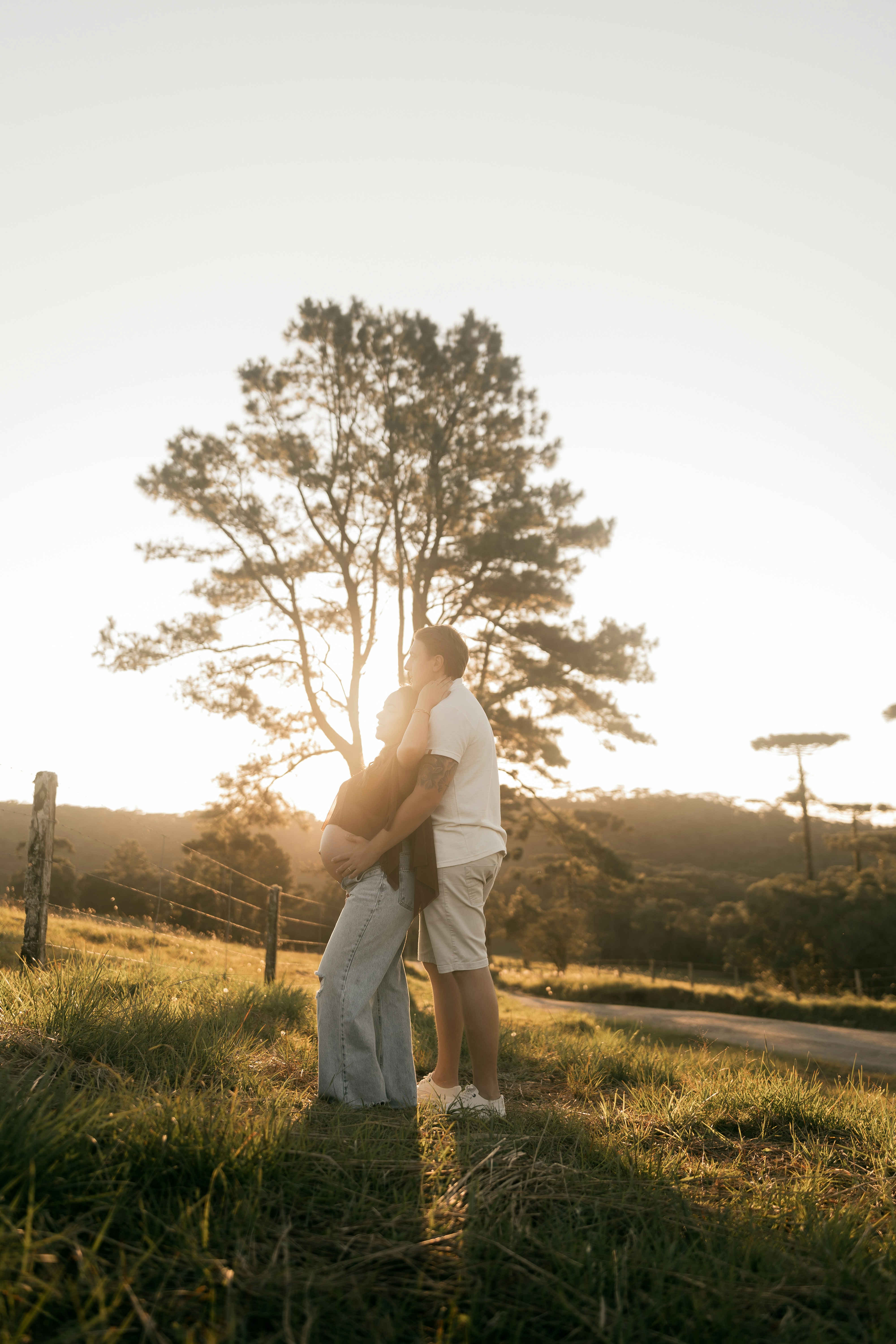 木のある陽差しの下の野原で抱き合うカップル。