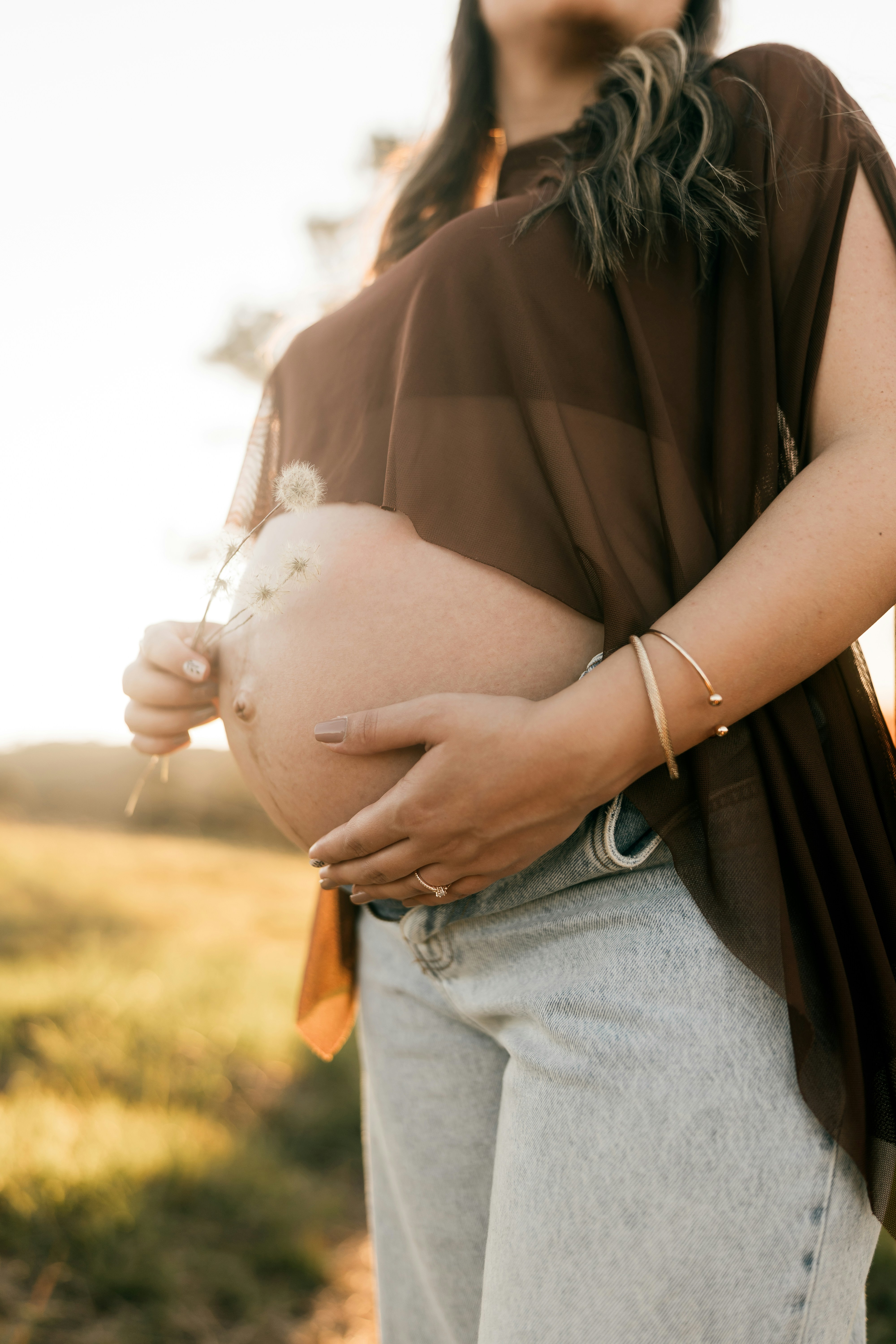 夕暮れ時にお腹を抱える妊婦
