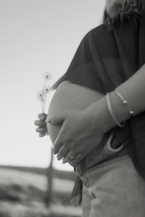 Pregnant belly with hands and small flowers