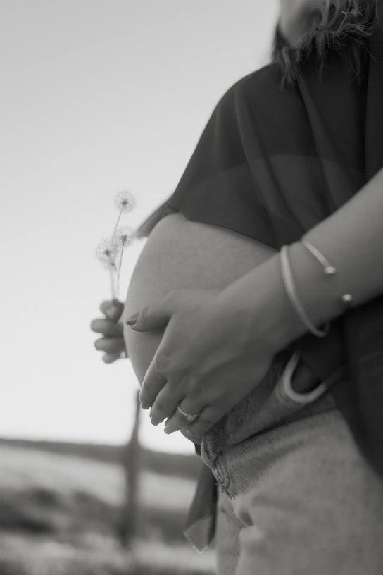 Pregnant belly with hands and small flowers